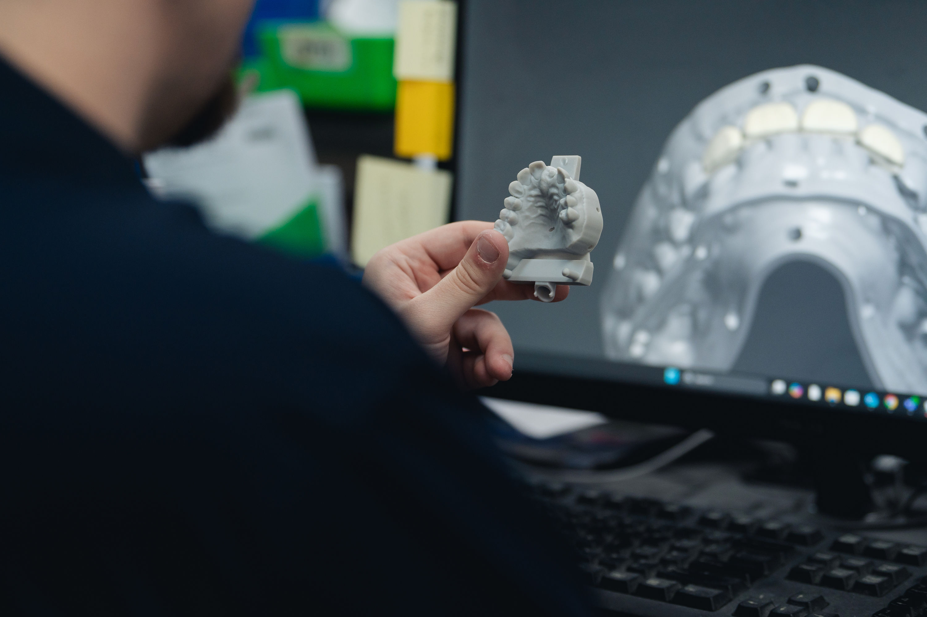 Gibson dental lab technician holding a dental model at a digital design workstation