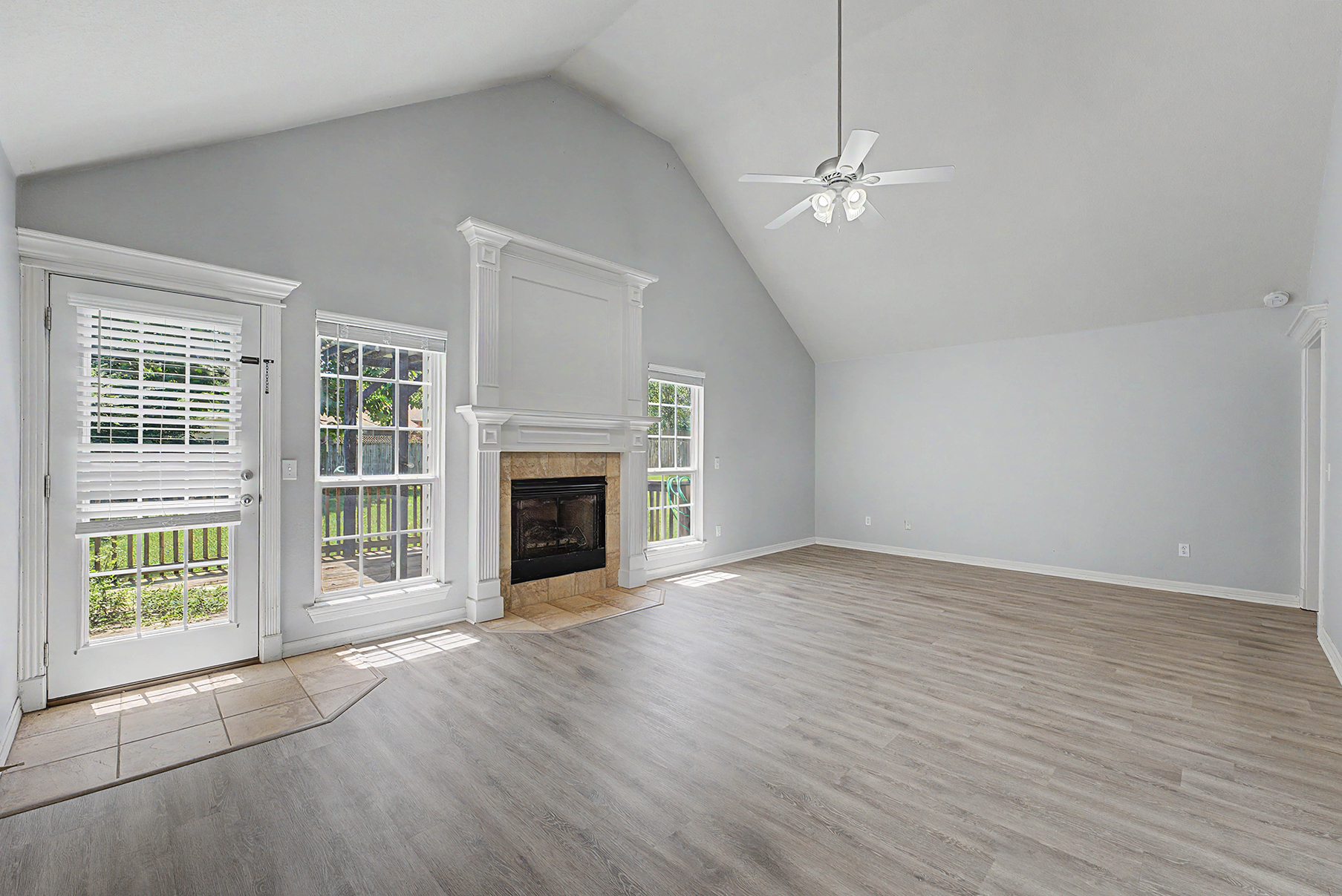 living room with high ceilings, brick fireplace, and three windows