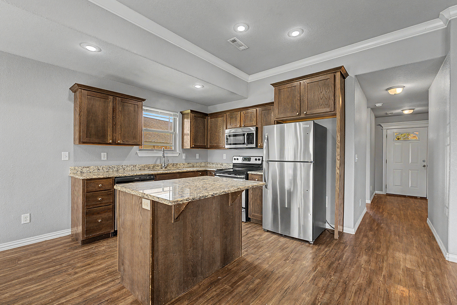 interior brown kitchen with island and stainless steel refrigerator