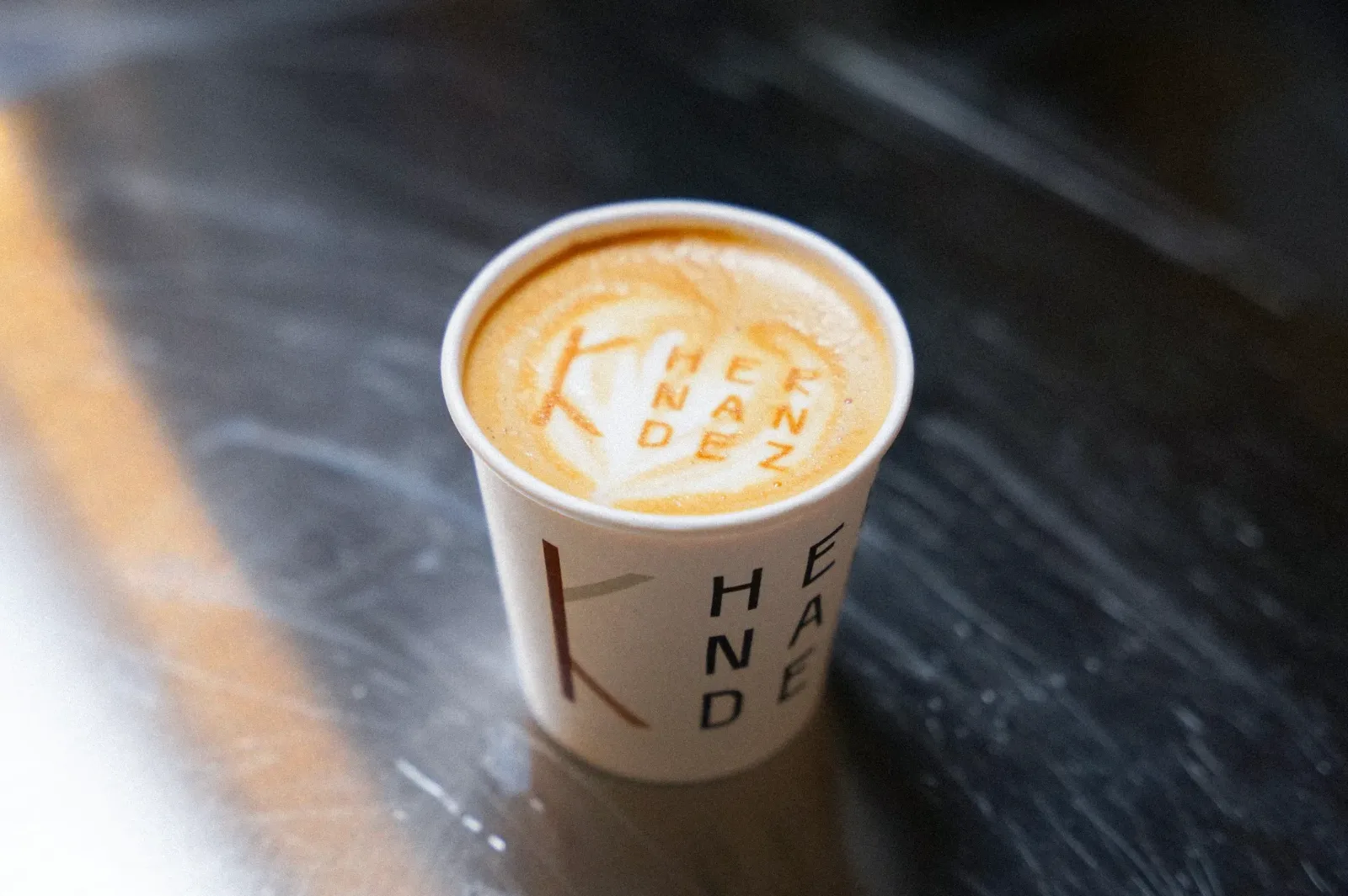 Latte in a custom-printed cup with the client's Hernandez logo printed in the foam