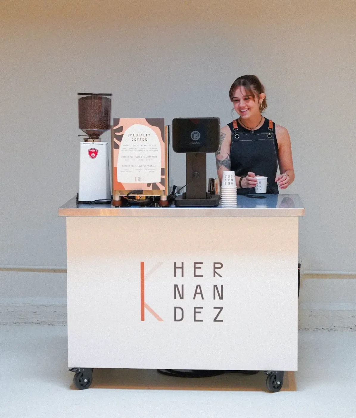 Barista behind a coffee cart with custom branded panels displaying a client logo