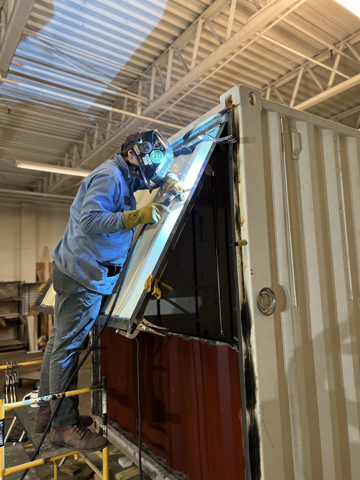 An ootBox fabricator welding a window frame in the Columbus shop