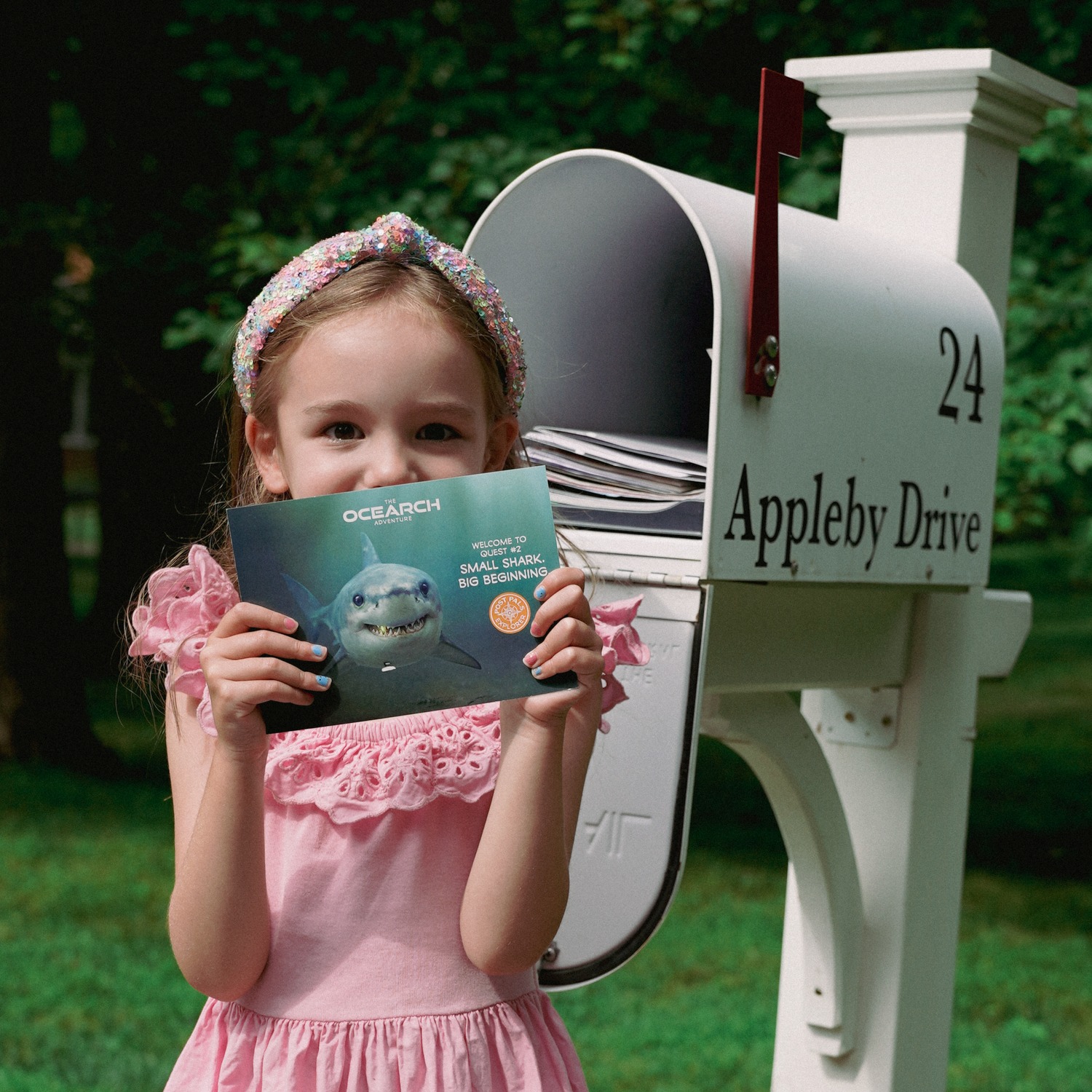 Young Explorer at her mailbox holding a POSTPALS OCEARCH shark postcard