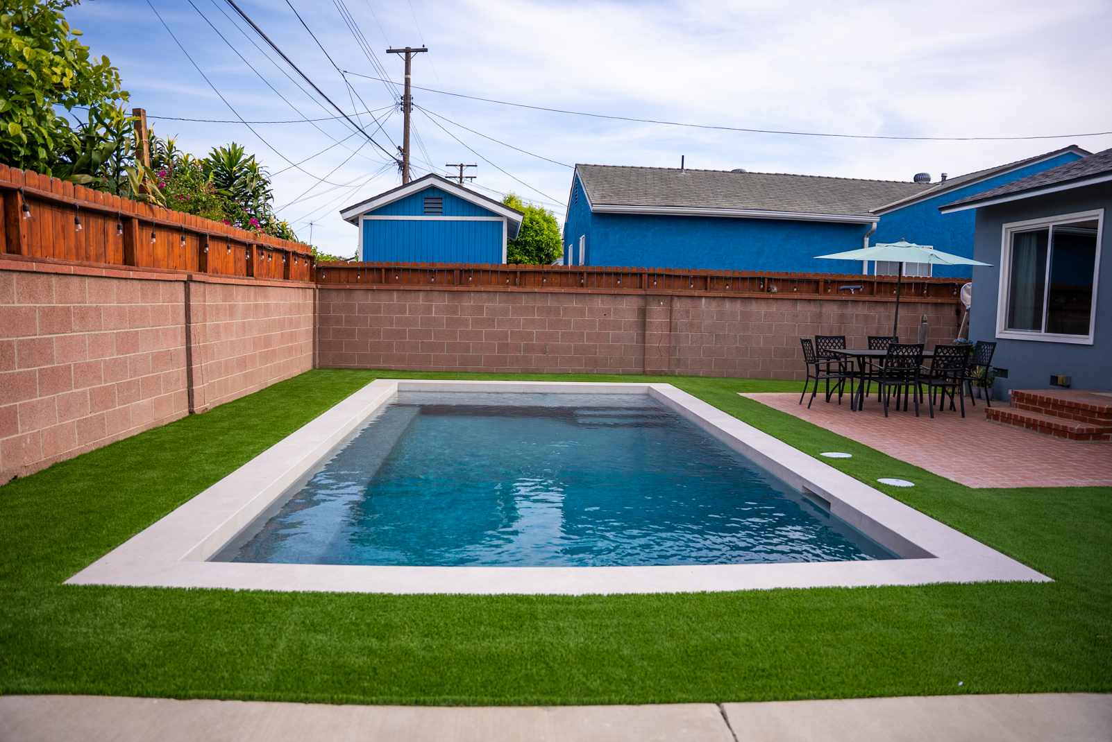 A rectangular pool fitted into a planted courtyard beside a covered outdoor living space.