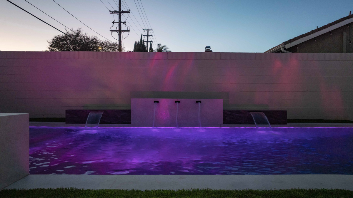 The pool lit magenta after dark, the colour washing up the rear wall behind three scuppers.