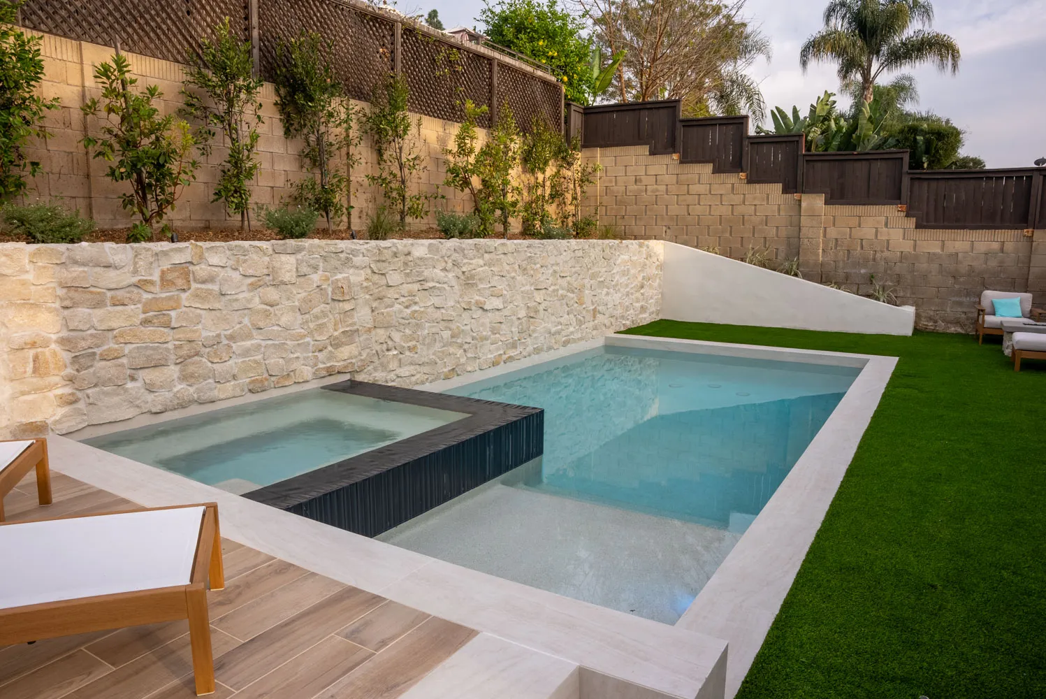 The spa and pool from the corner of the deck, turf wrapping the near edge.