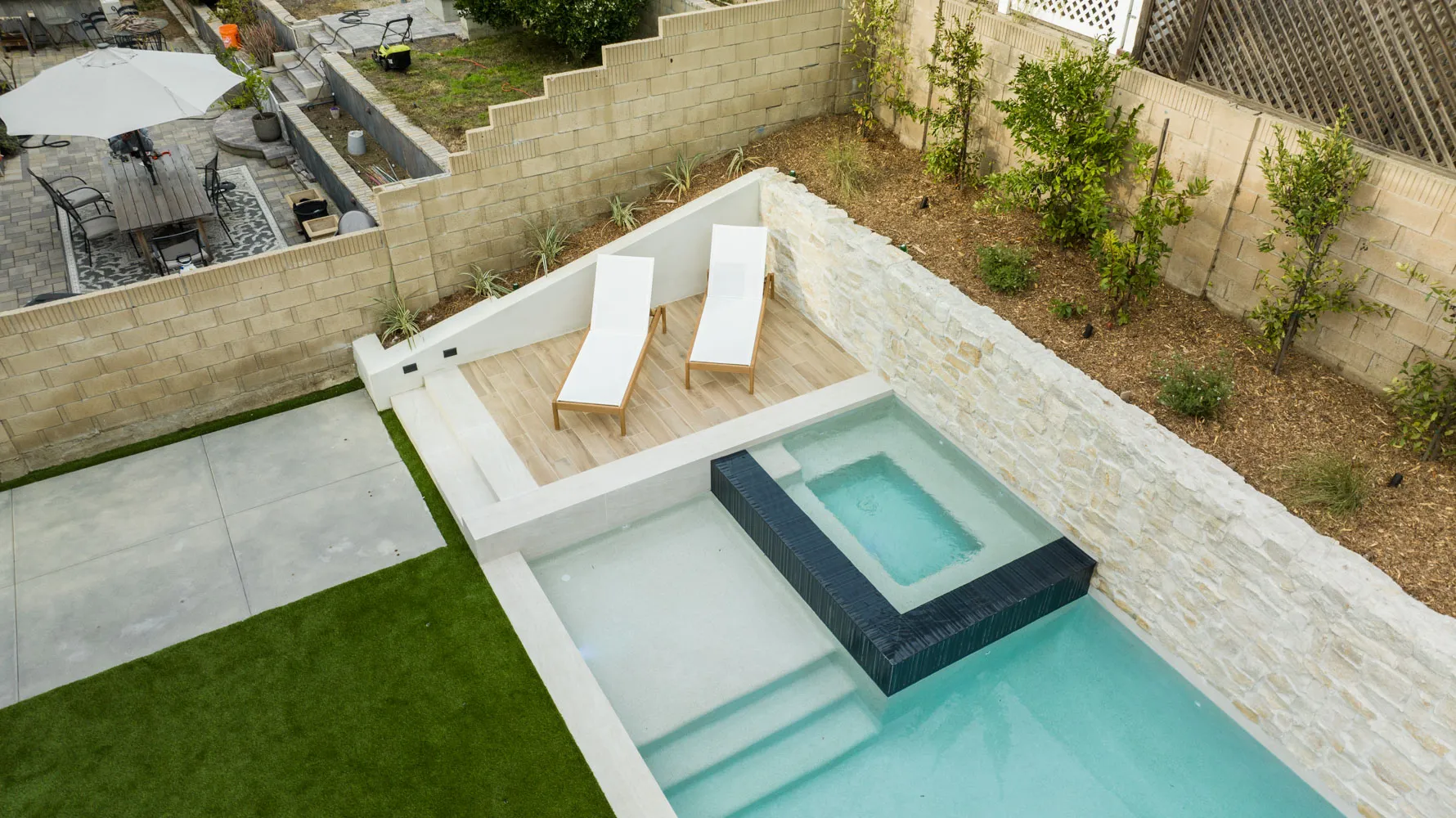 The spa and loungers from overhead, set into turf and pale paving.