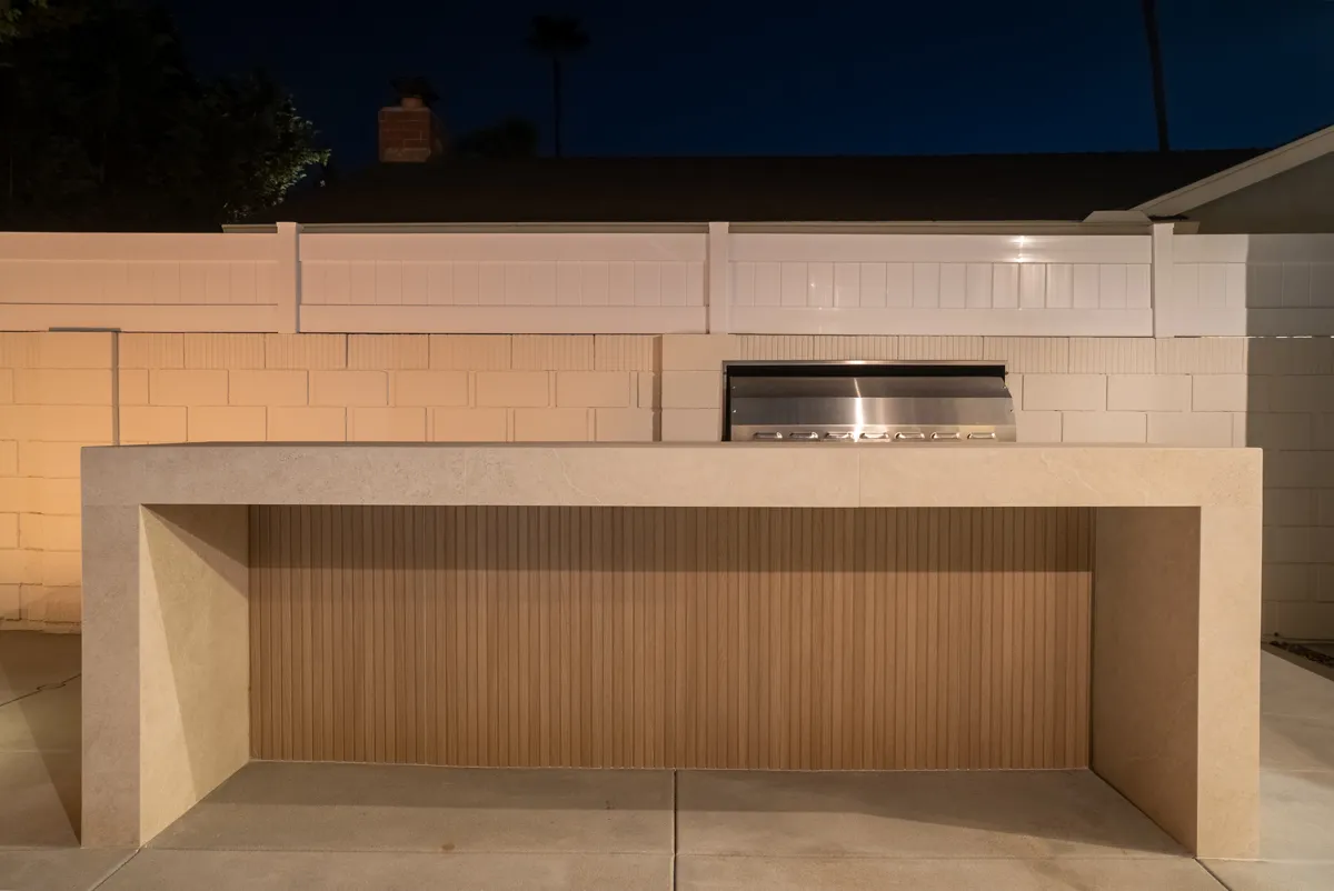 The outdoor kitchen counter with its built-in grill, set against a painted block wall.