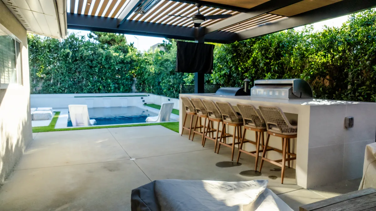 The kitchen and bar under the pergola, looking out across the pool to the hedge.