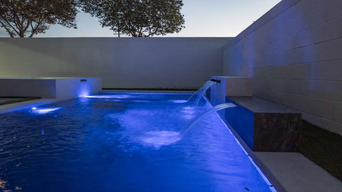The same pool lit blue, the sheet falls catching the light against a pale rear wall.