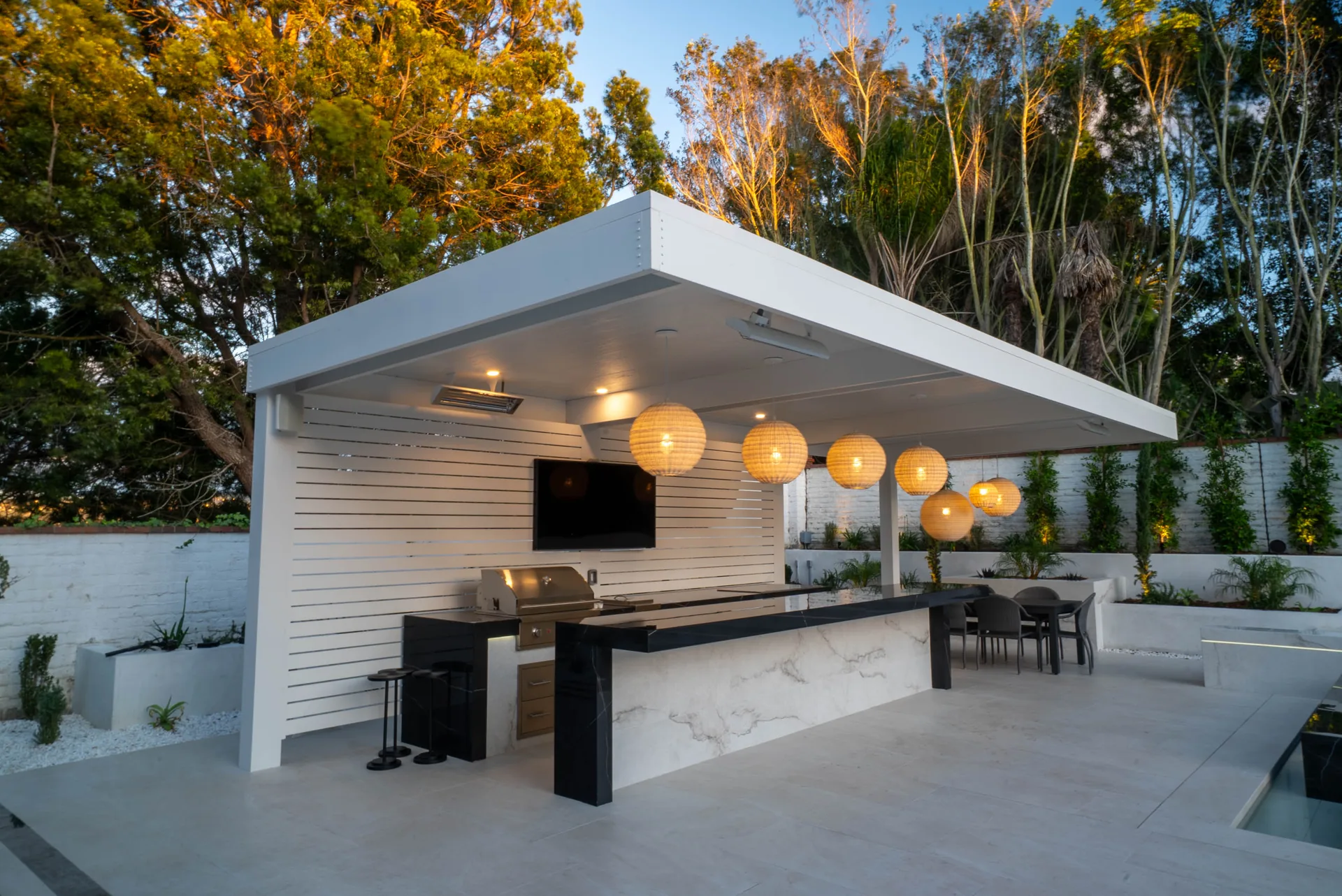 The pavilion from the deck, its flat white roof carrying a row of globe lanterns over a marble bar and grill.