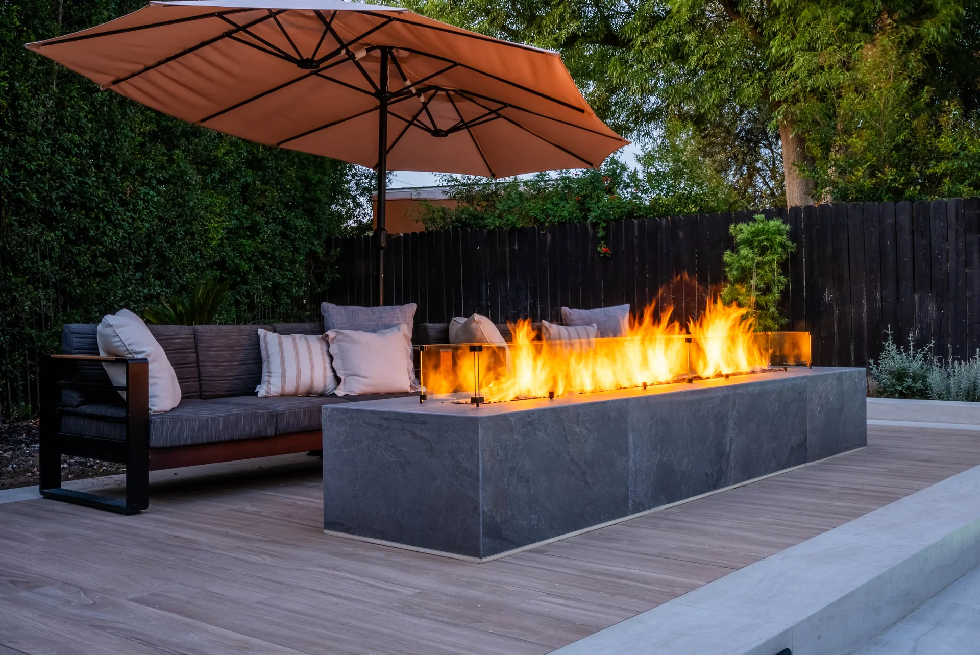 The fire trough burning at full height beside the sofa, a large parasol tilted overhead.