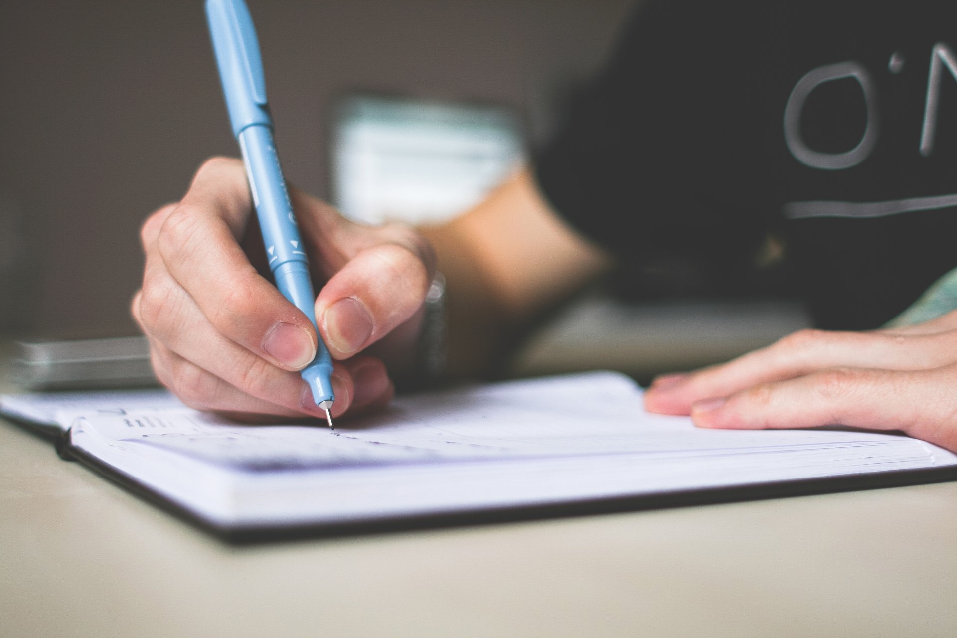 An open notebook with a pen on a wooden table.