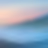 Vue floue de vagues douces avec un ciel coloré en arrière-plan, tons pastel de bleu, rose et orange.