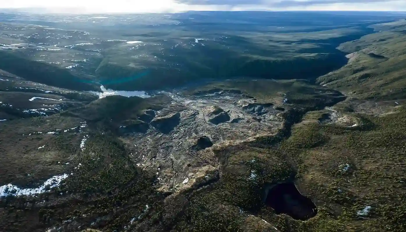 Aerial view of a kilometre-scale thaw slump running down a forested valley to a lake