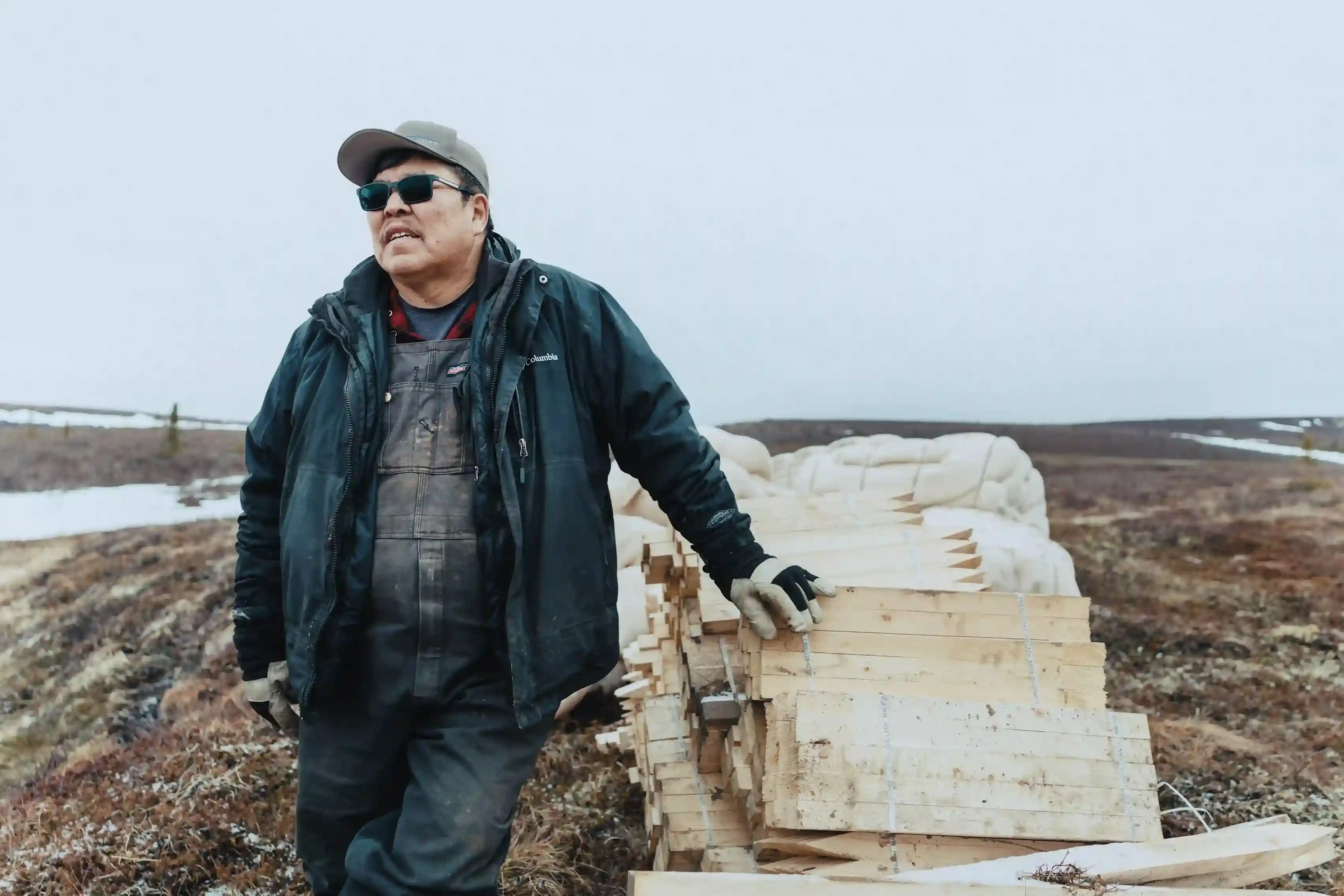 Portrait of James Ross beside a stack of lath on the tundra
