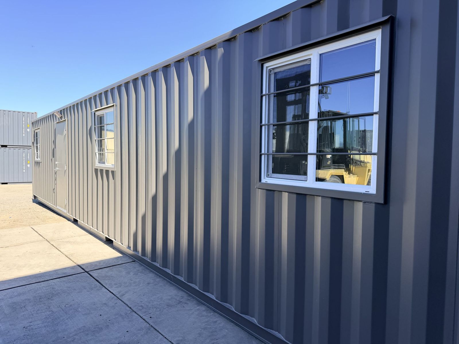 Forty foot container office finished with painted walls, butcher-block desks, a reception counter, and a mini split