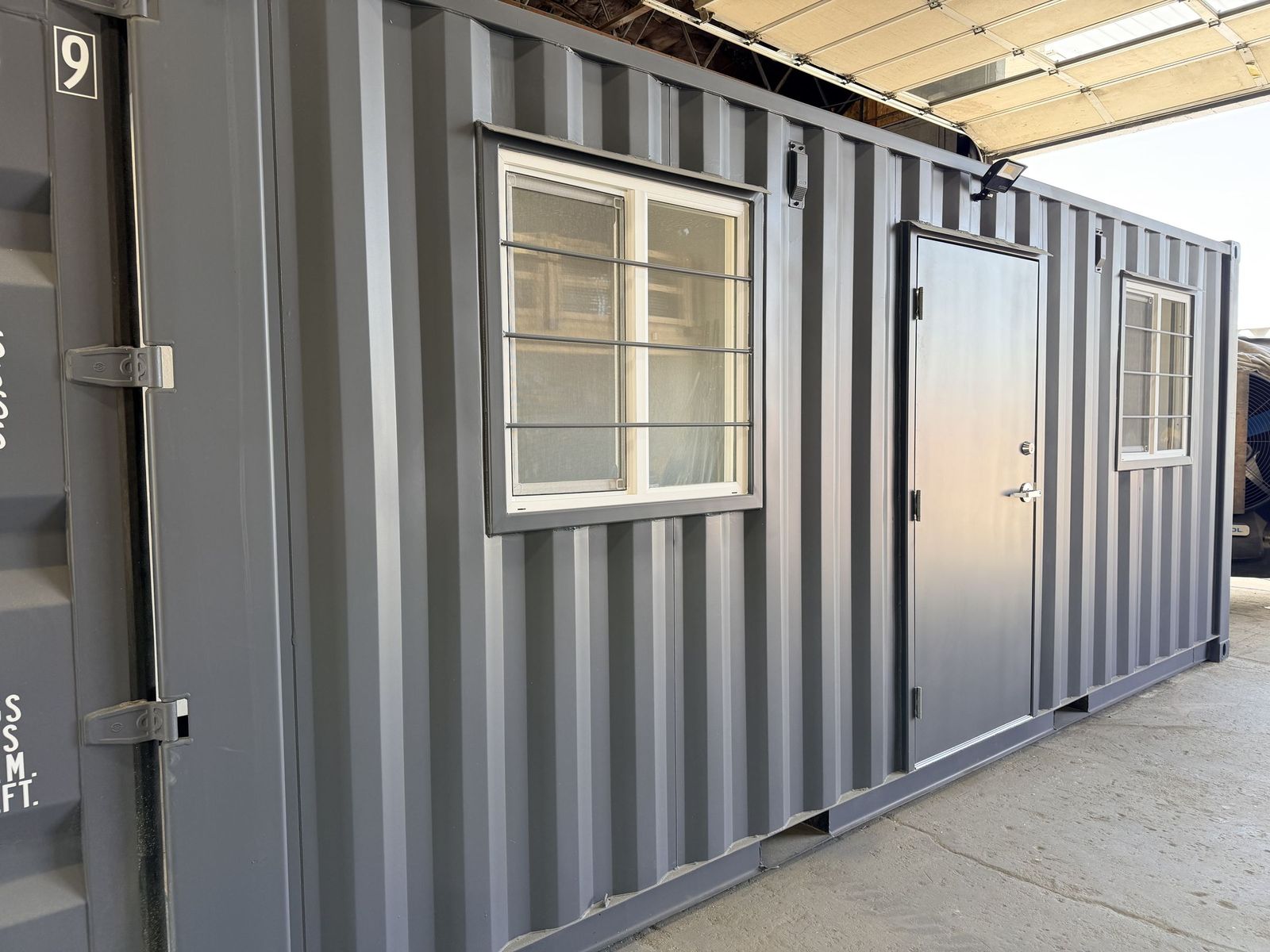 Container office interior with a green reception counter, butcher-block tops, and a wrap-around desk