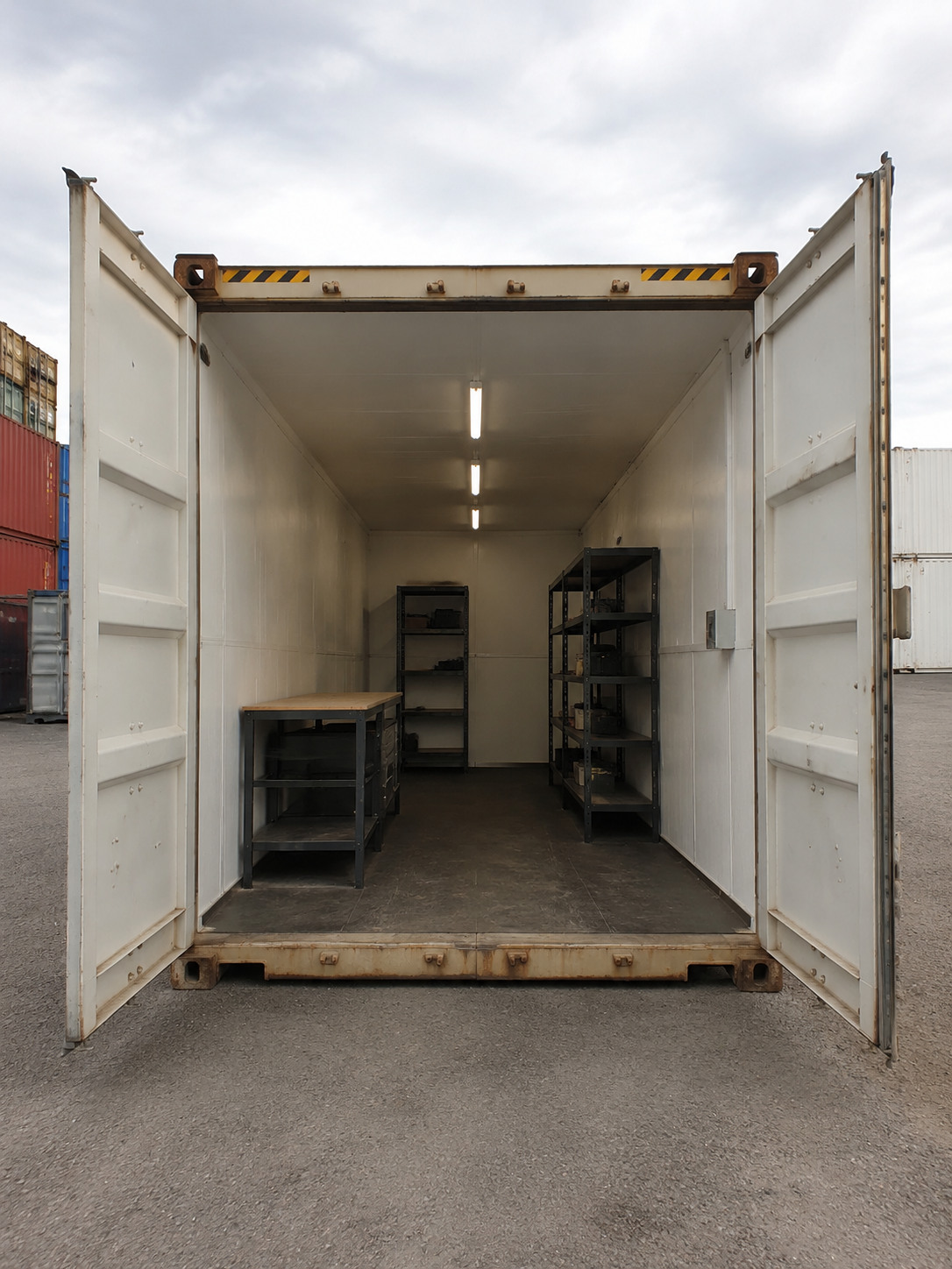 Insulated container workshop with a bench and steel shelving