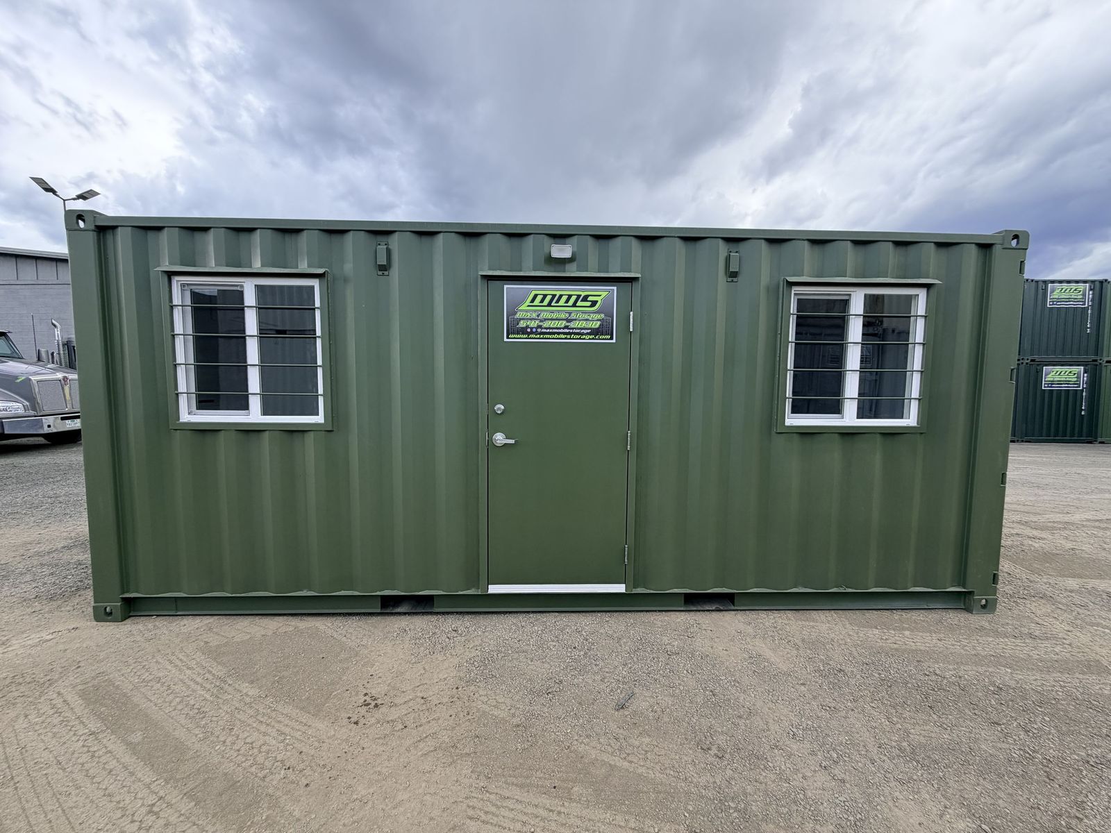 Compact container office with windows on both walls, a work surface, and a wall-mounted mini split