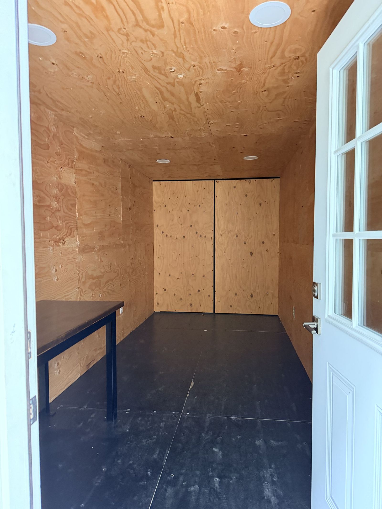 Container office interior with a plywood partition wall separating the office from the storage end