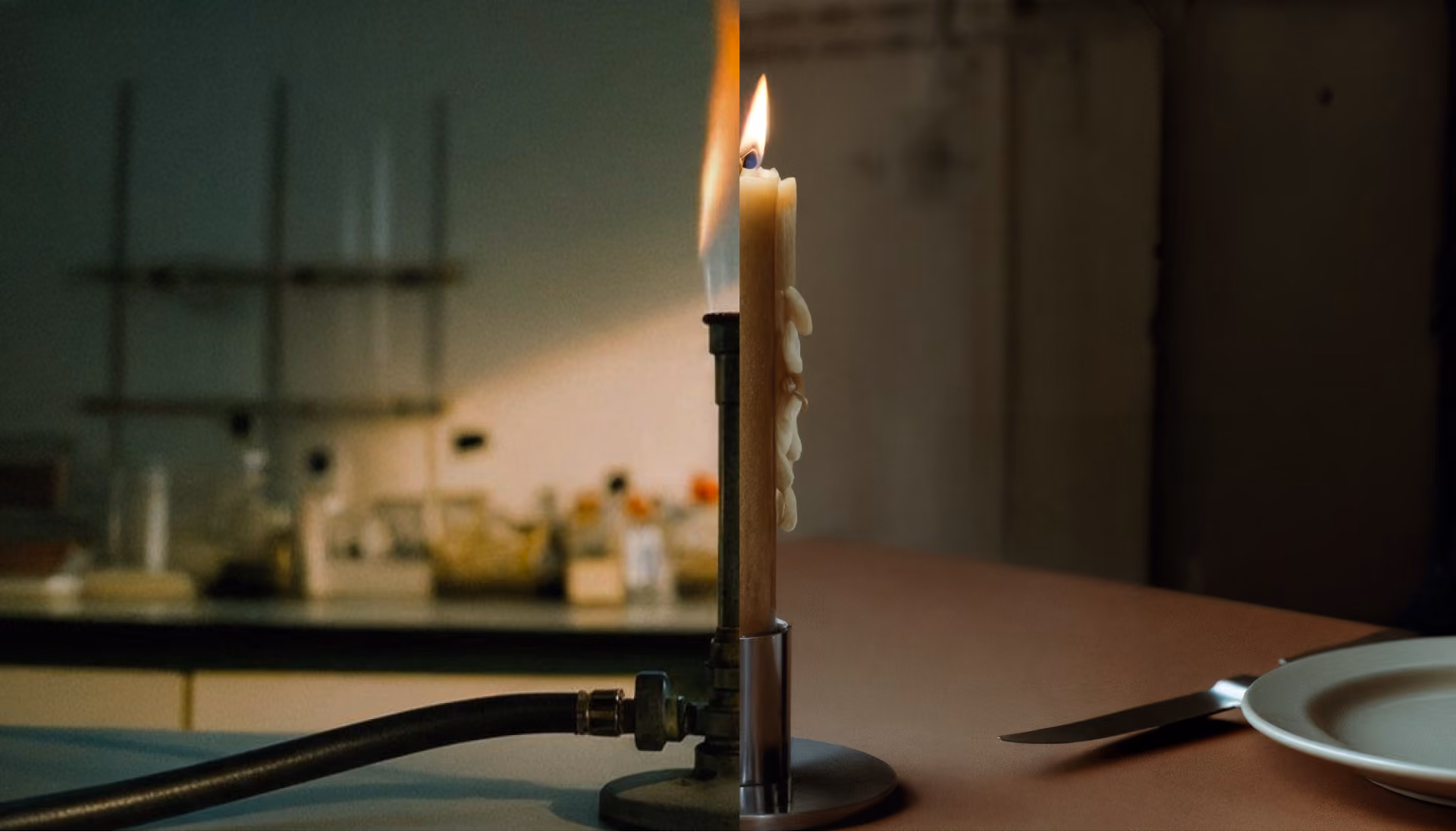 A lit candle burning atop a laboratory Bunsen burner on a table, with a blurred background of lab equipment to the left and a fork and empty plate to the right on the table.
