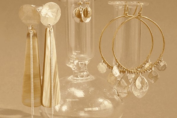 Chan Luu gold earrings displayed on glass