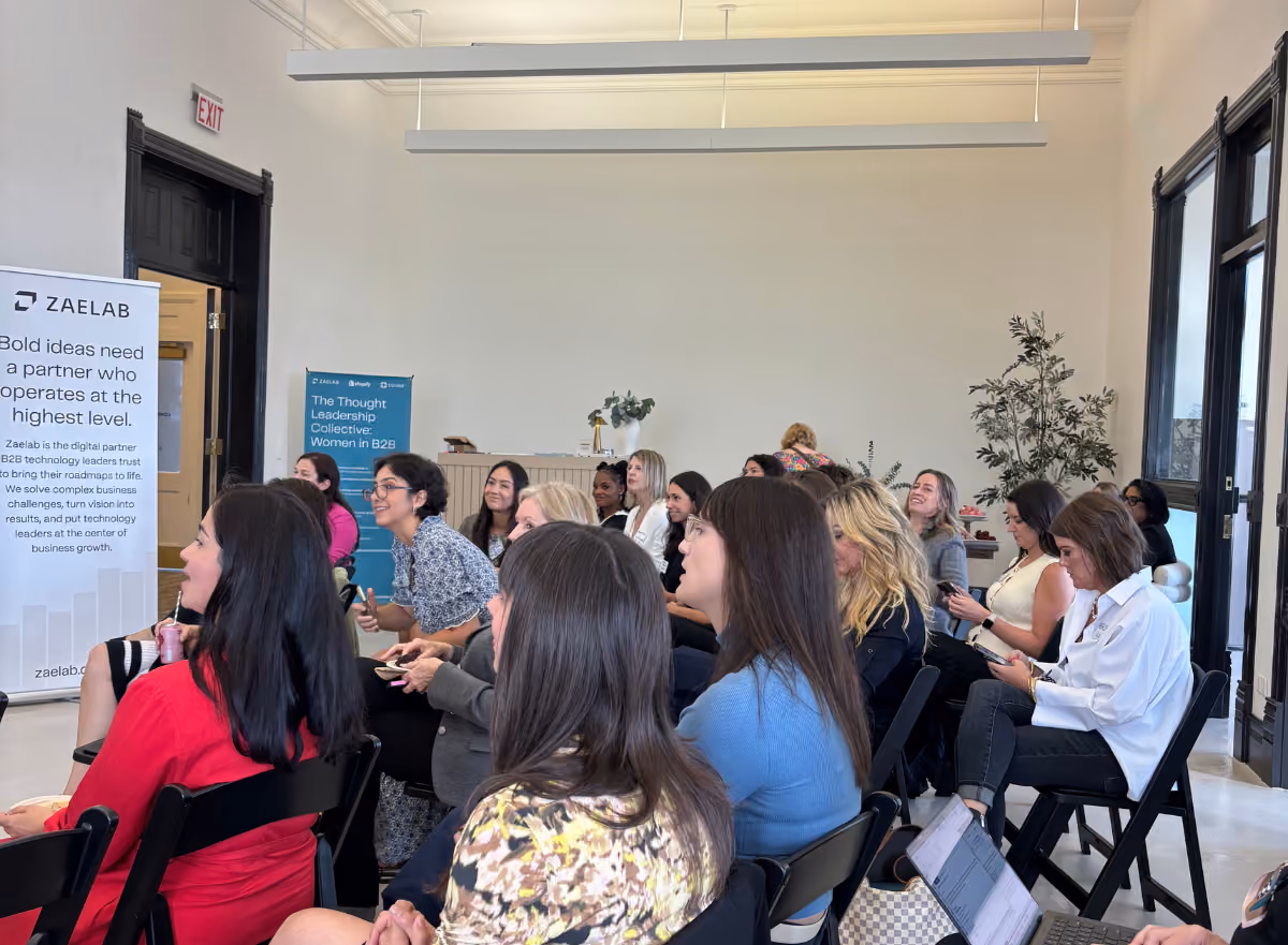 Attendees engage and smile while listening to a panel at the Women in B2B event, with Zaelab and event banners in the background.