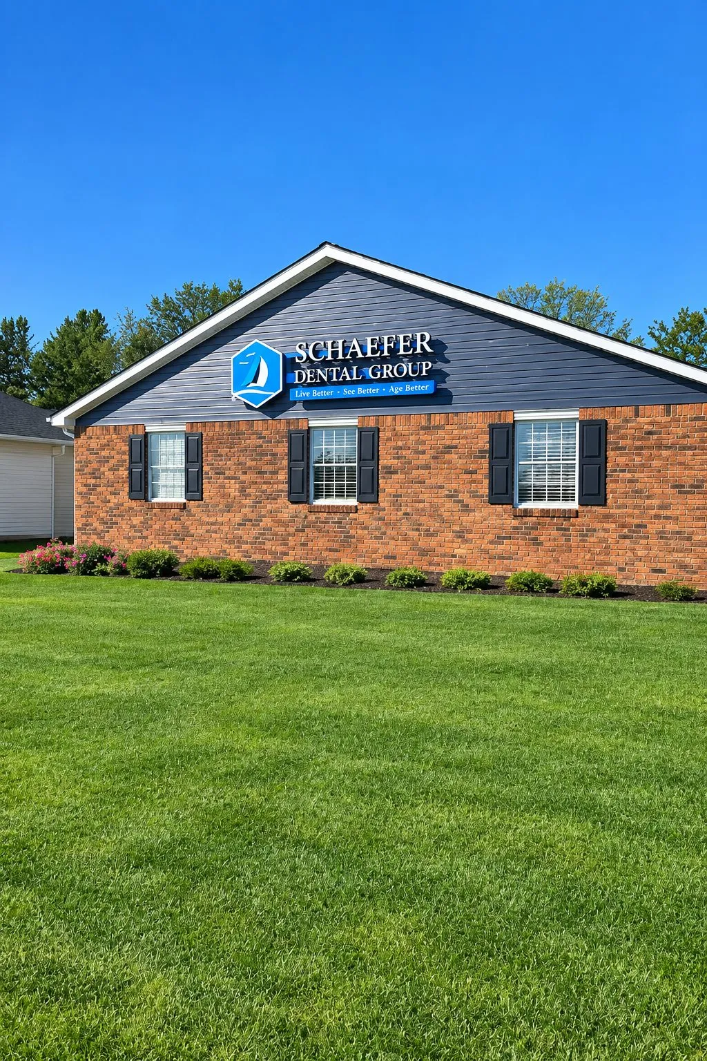 Exterior of Schaefer Dental Group in Brighton, MI, with the office sign above the brick building and lawn.