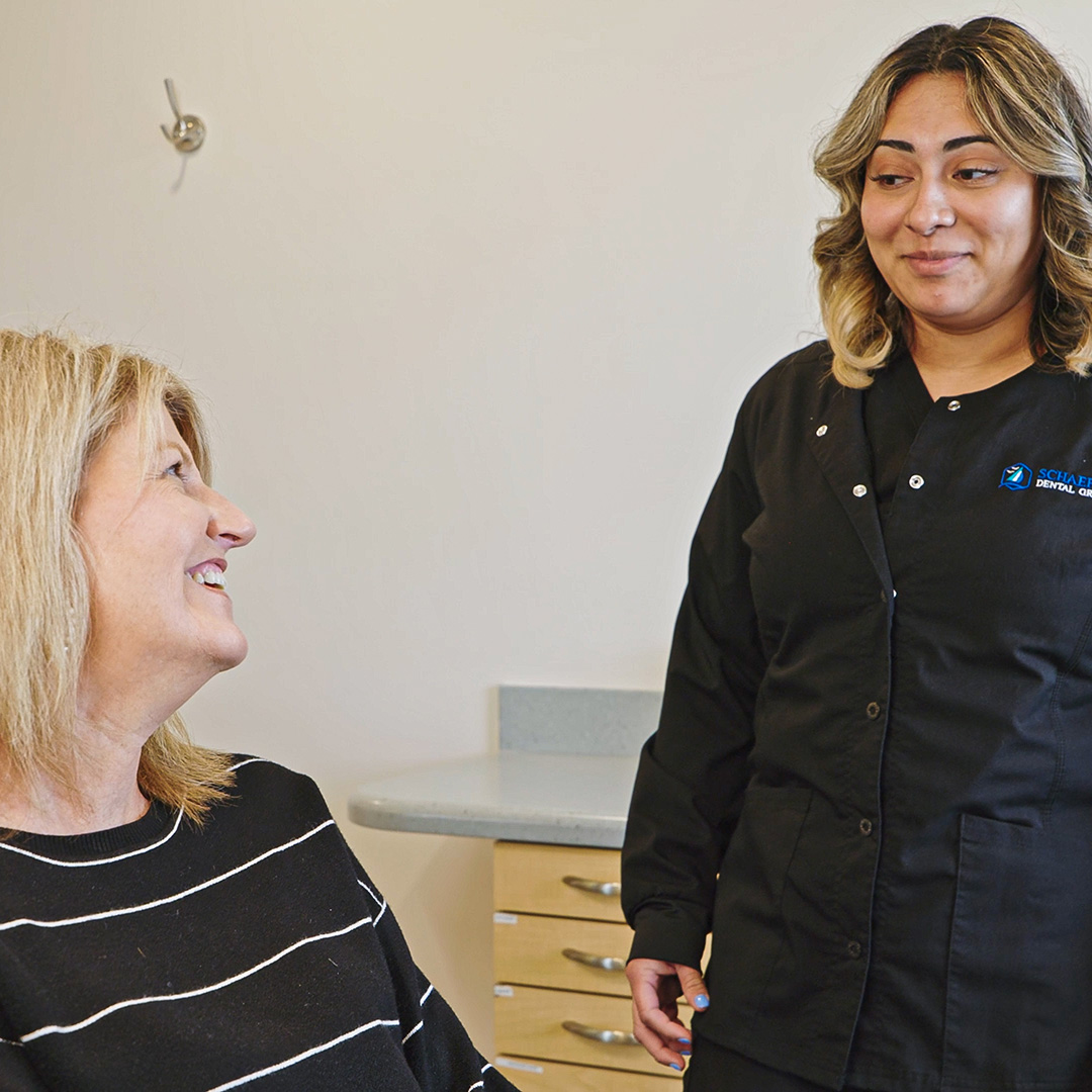 Schaefer Dental Group team member talking with a smiling patient in a treatment room in Brighton, MI.