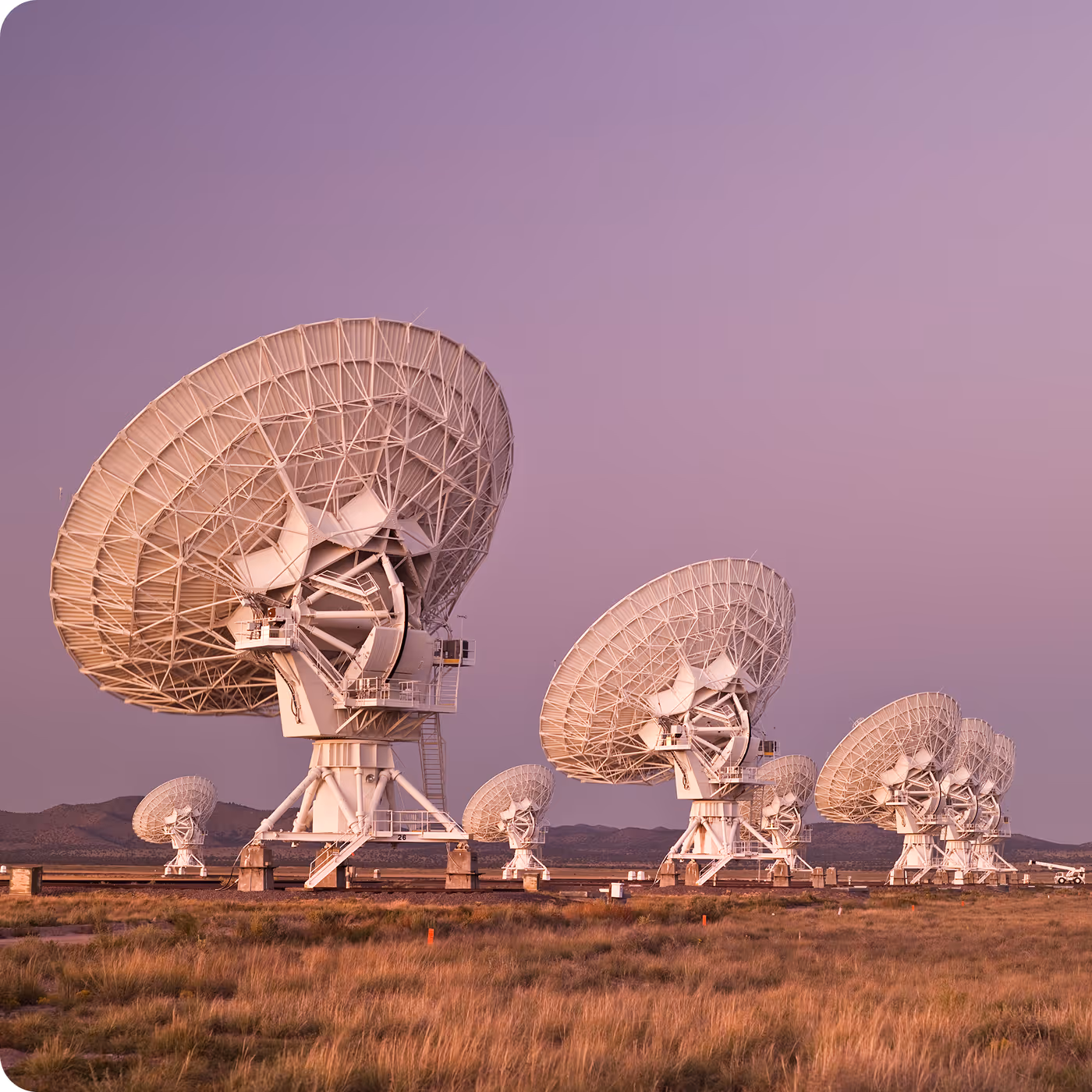 A field of large satellite dishes under a dusk sky