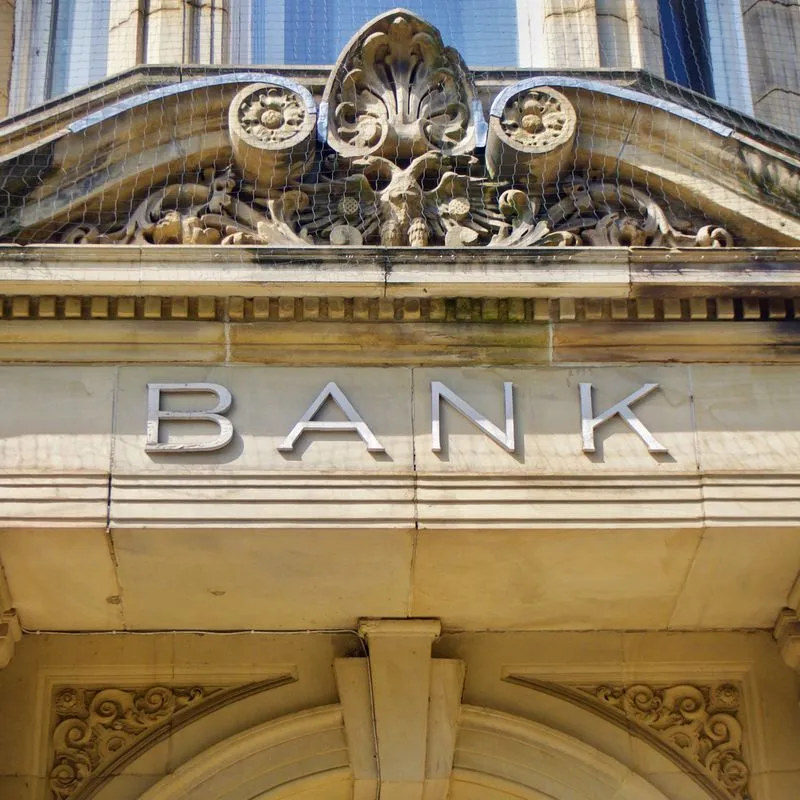 Close-up of an ornate stone building facade with BANK carved into the masonry