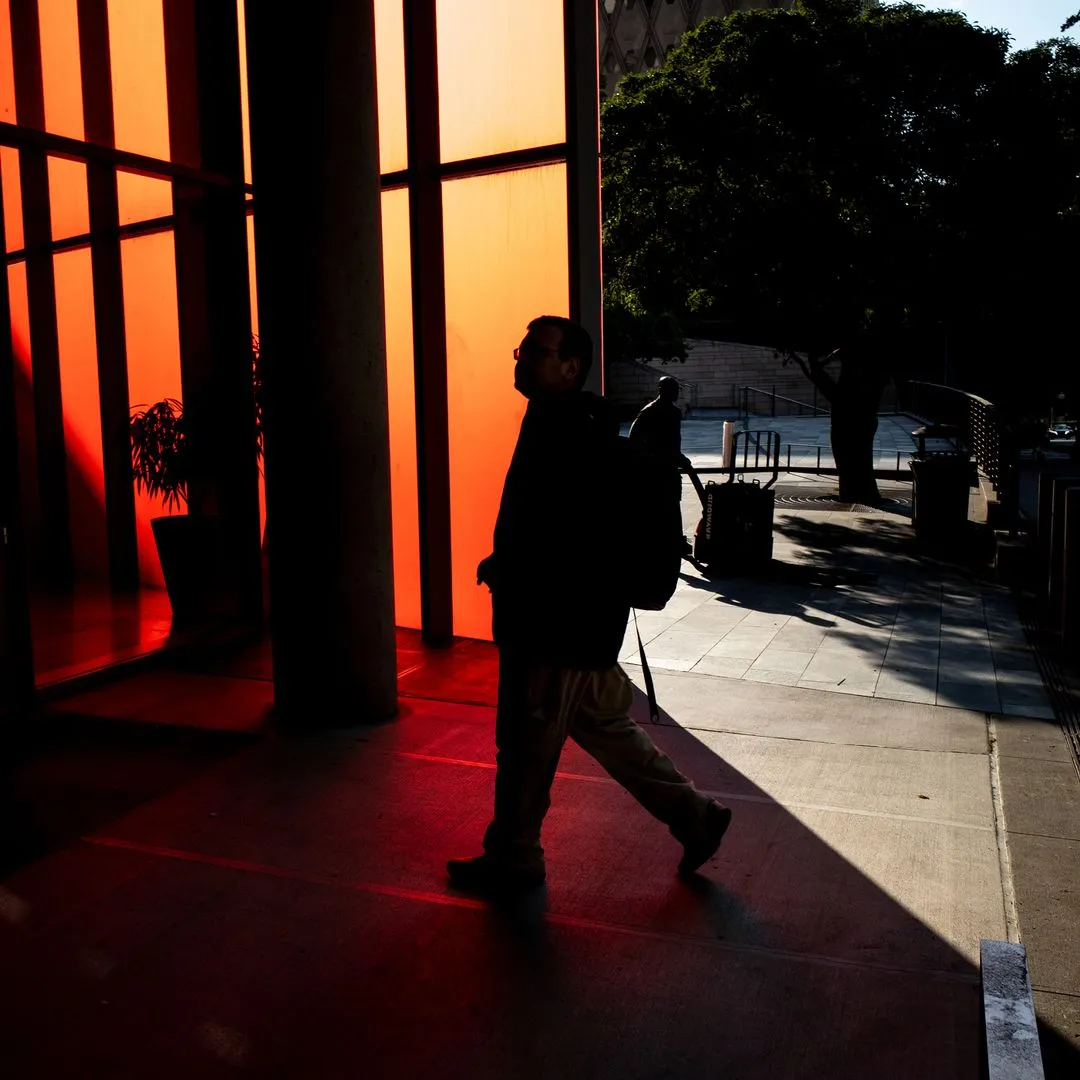 A person with a backpack walking through a building entrance lit by warm sunset light