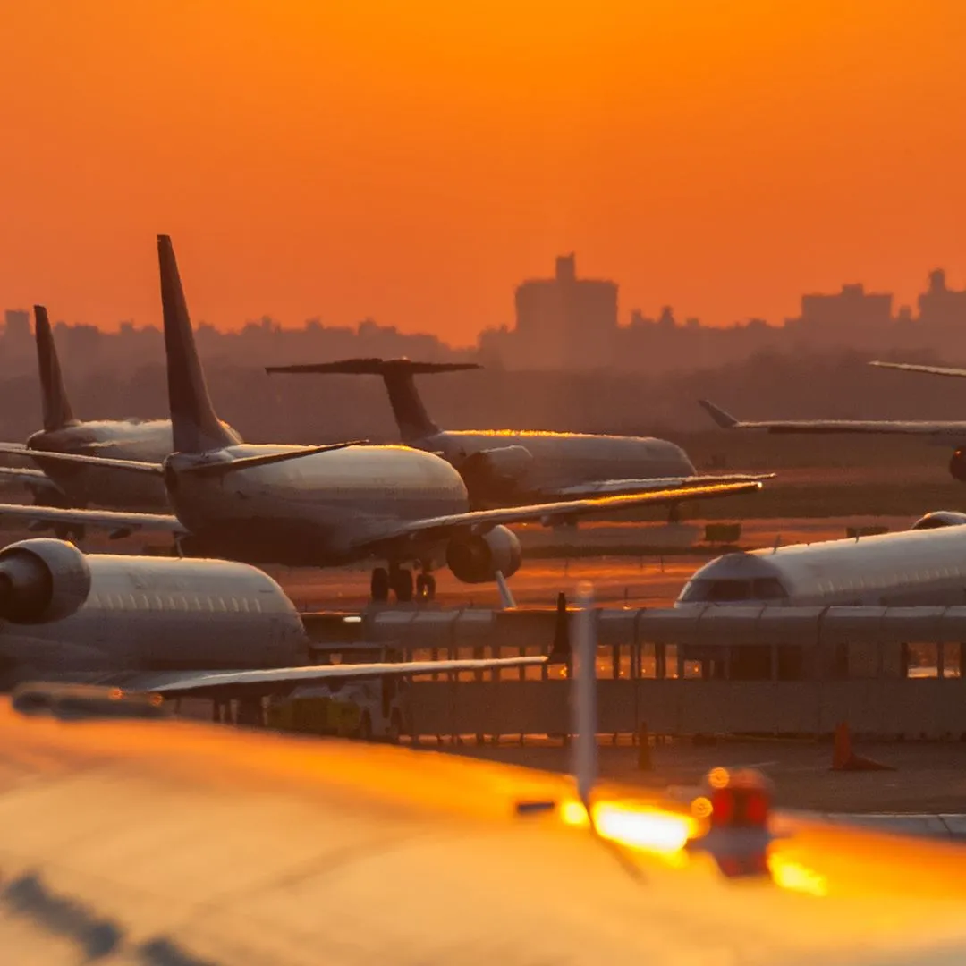 Passenger aircraft parked on an airport tarmac at sunset