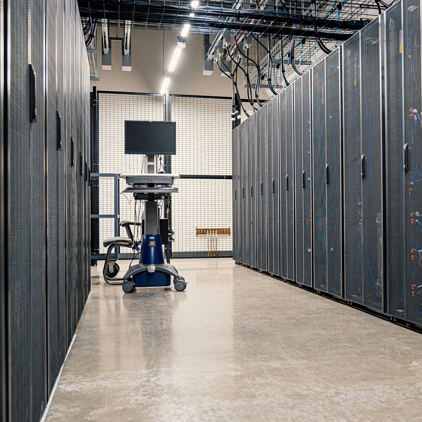 An aisle of server racks in a data center with a mobile workstation cart