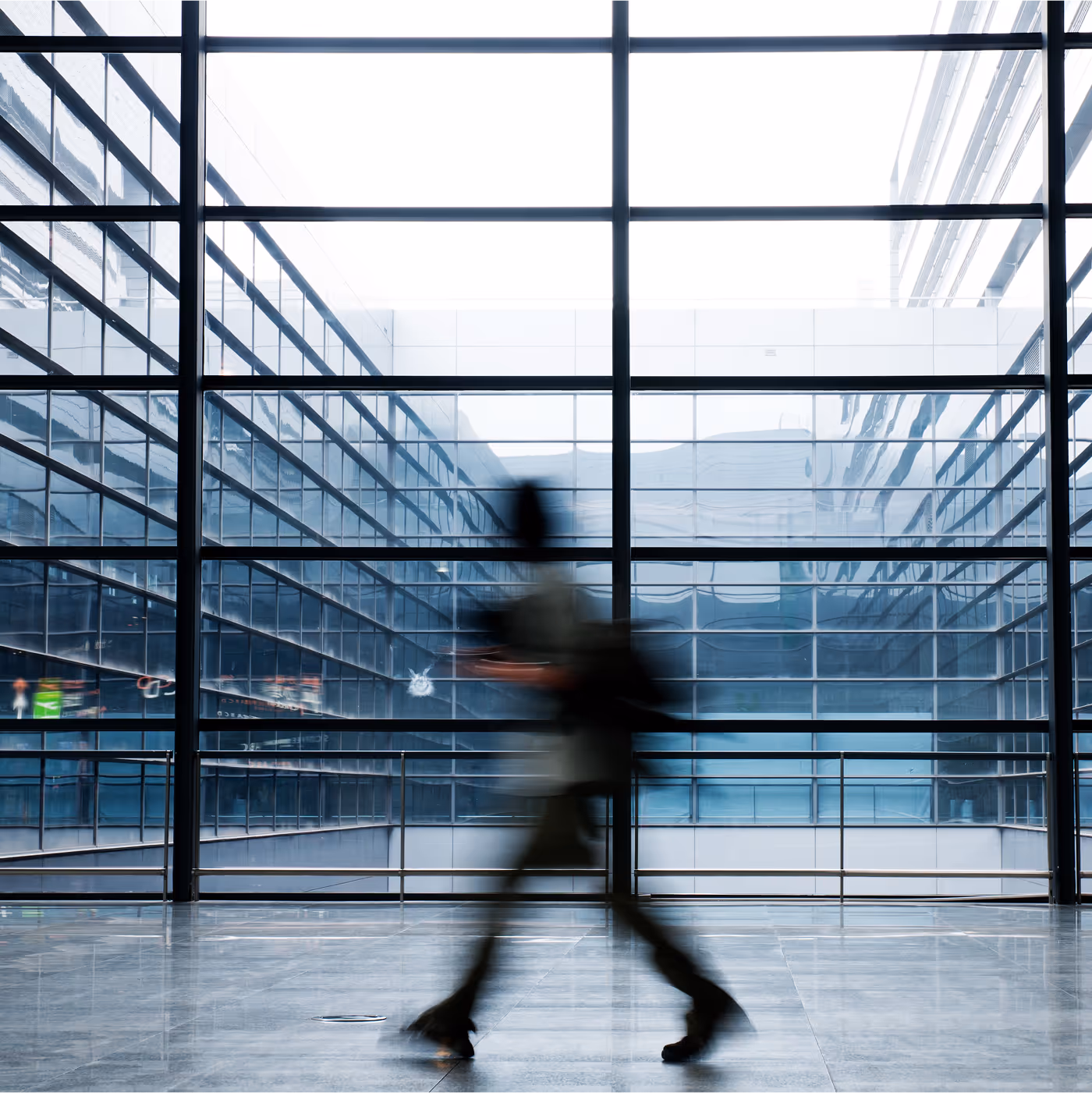 A person walking through a glass-walled corporate atrium, captured in motion blur
