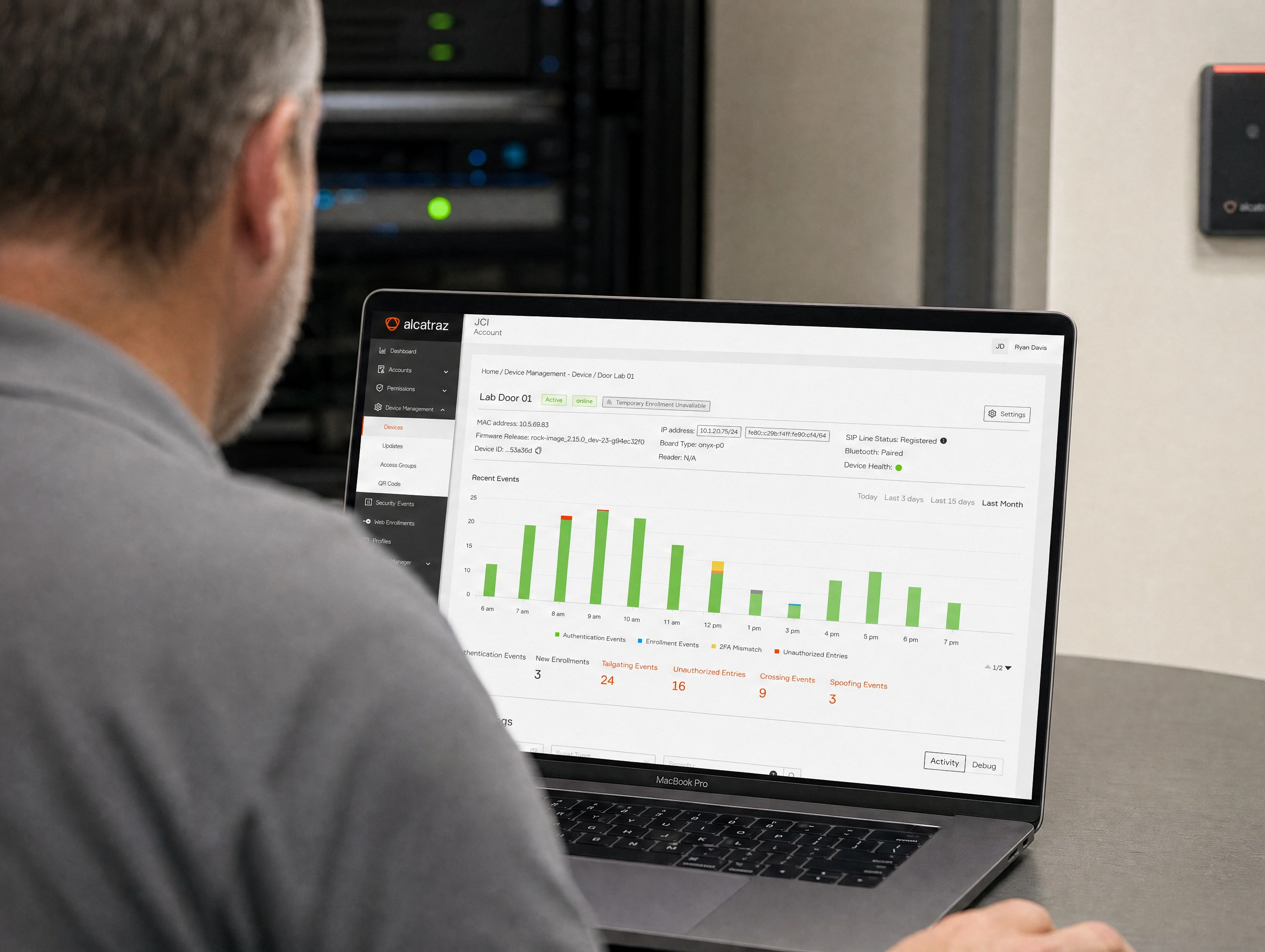 An administrator managing a Rock device in Rock Cortex on a laptop, beside a server rack