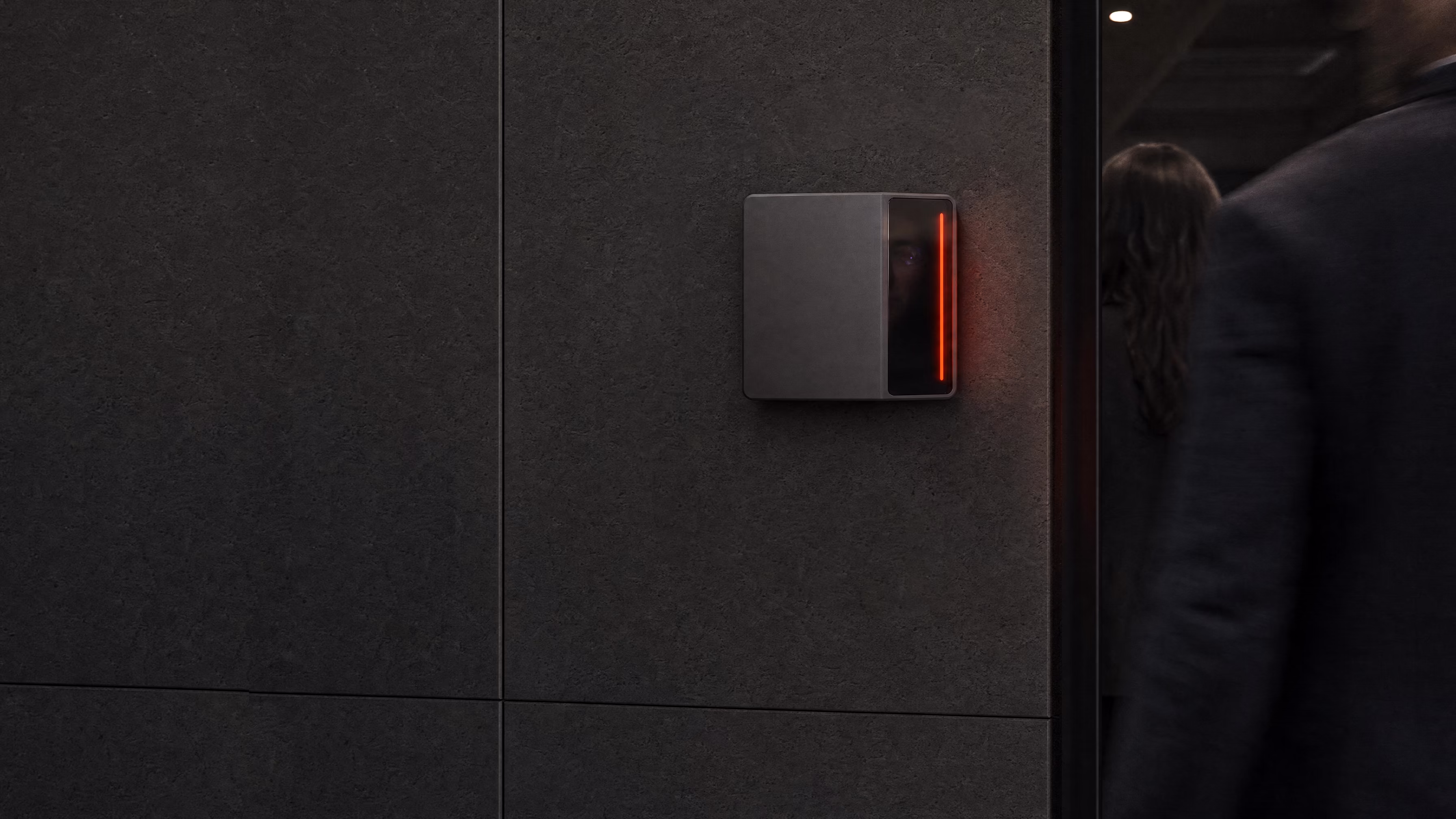 A Rock X reader on a dark stone wall glowing red as a second person follows someone through the doorway