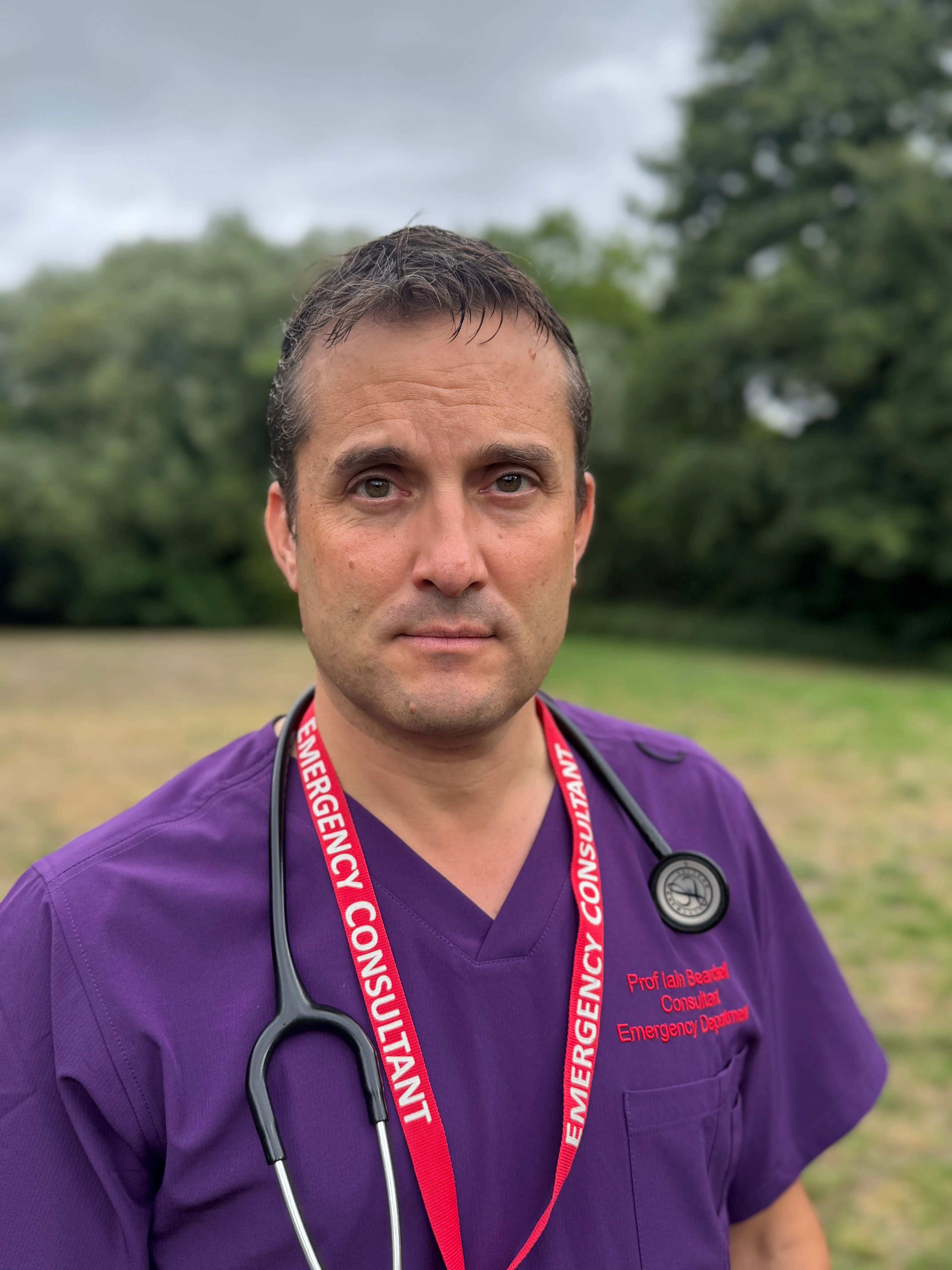 Iain Beardsell wearing clinical scrubs and a stethoscope.