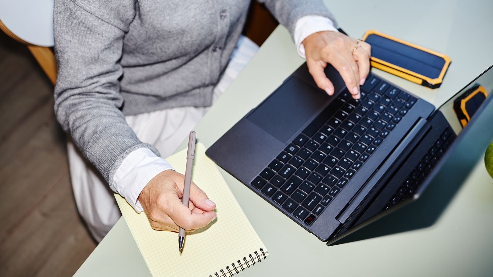 Medewerker maakt notities naast een laptop