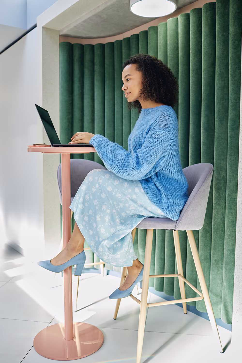 Vrouw werkt aan een laptop aan een statafel in een moderne kantoorruimte