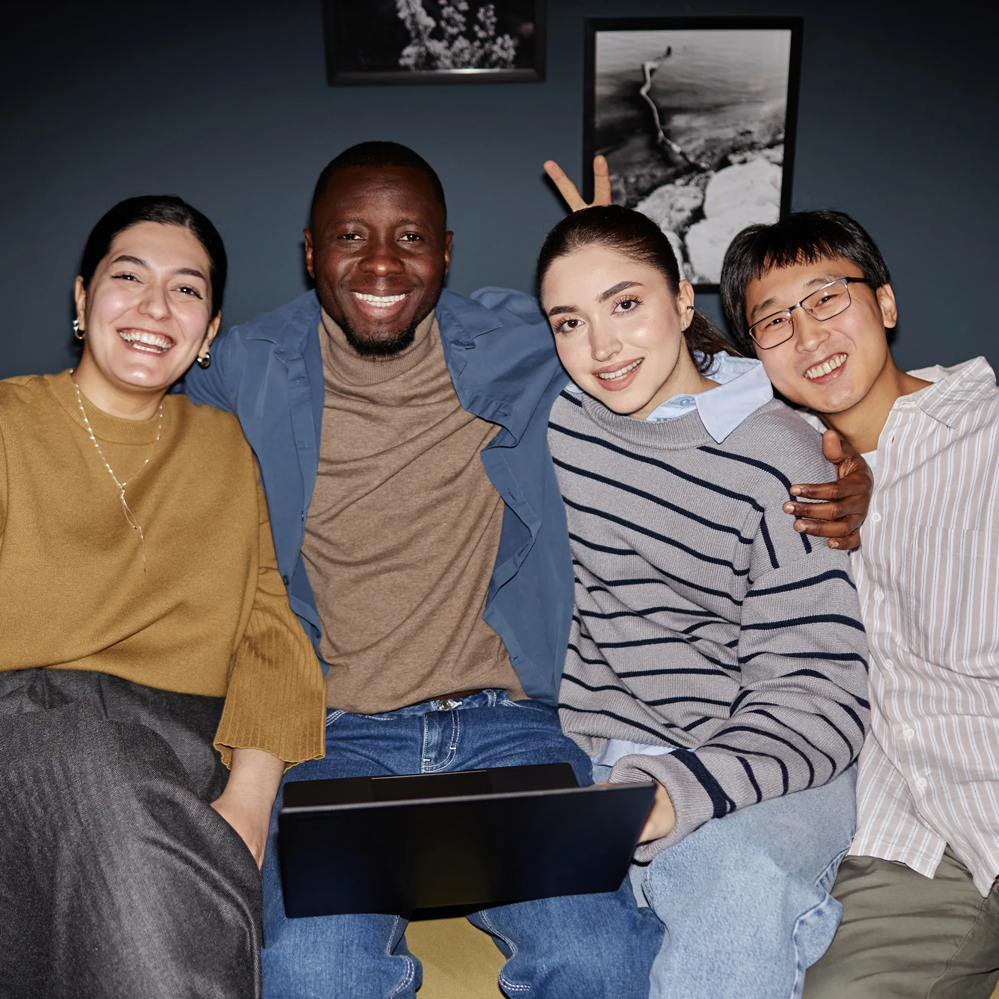 Vier collega's poseren lachend samen met een laptop