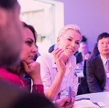 Smiling woman listening among attendees at a conference table