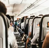 Passengers seated along the aisle of a full aeroplane cabin