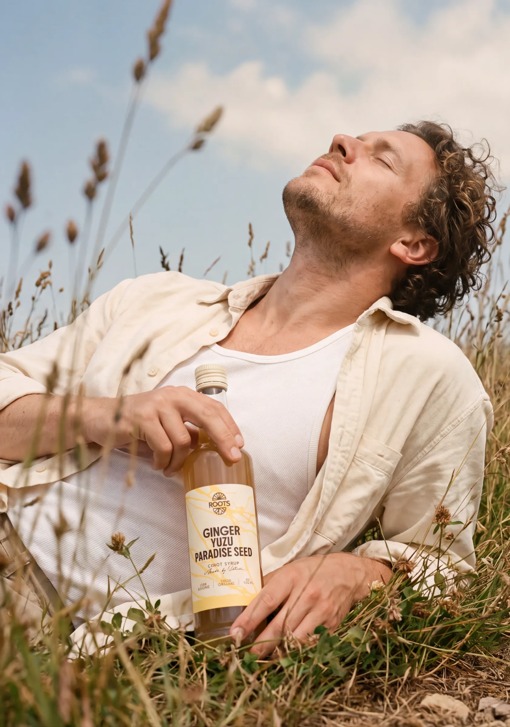 Man ligt ontspannen in het gras met een fles Roots Ginger Yuzu