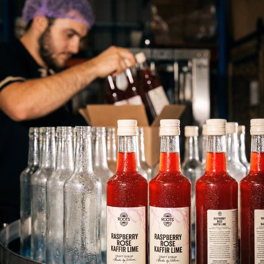 Medewerker vult flessen Roots Raspberry Rose Kaffir Lime af in de fabriek