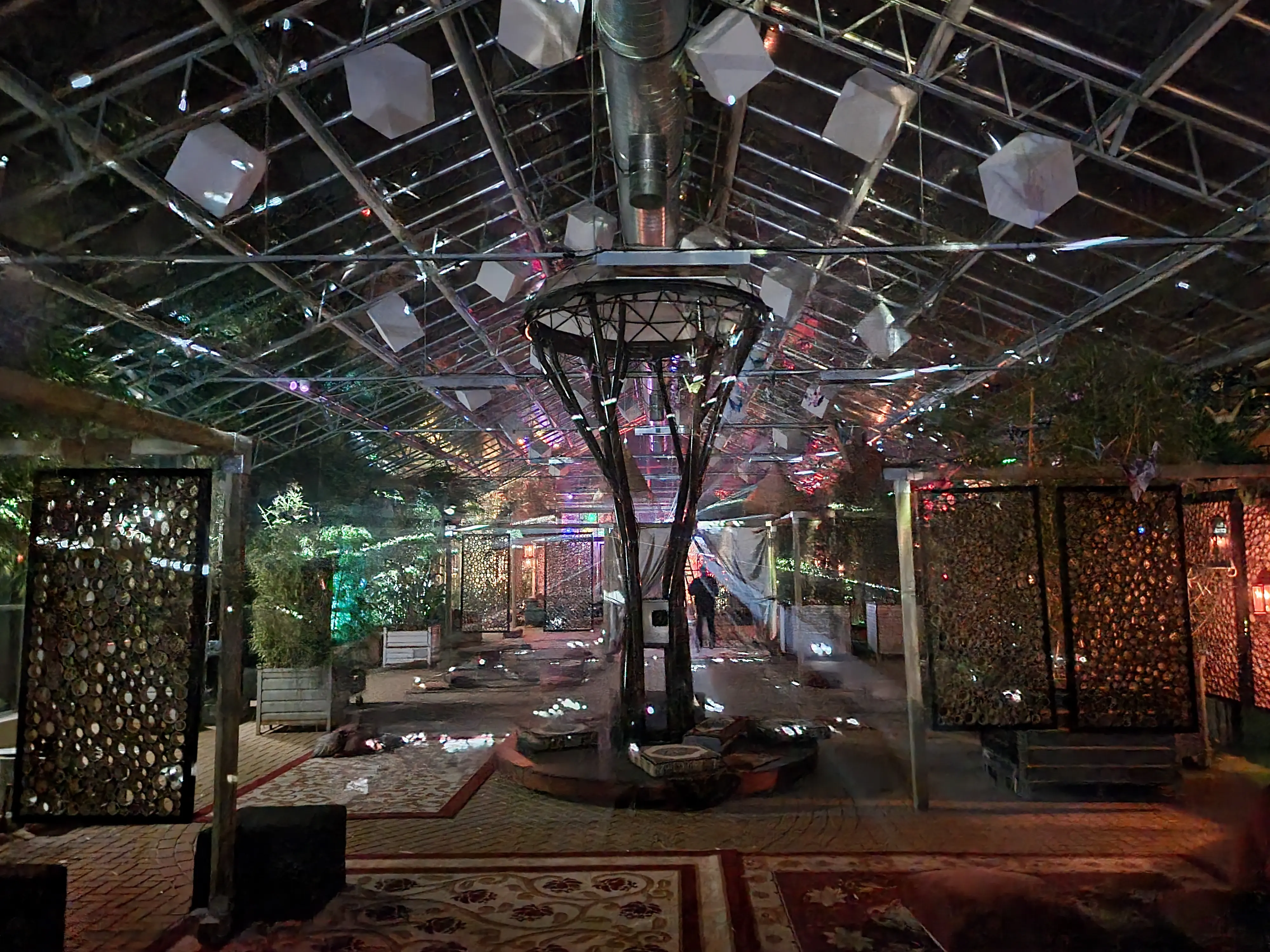 Sfeervol aangeklede festivalruimte met tapijten en lichtinstallaties onder een glazen dak