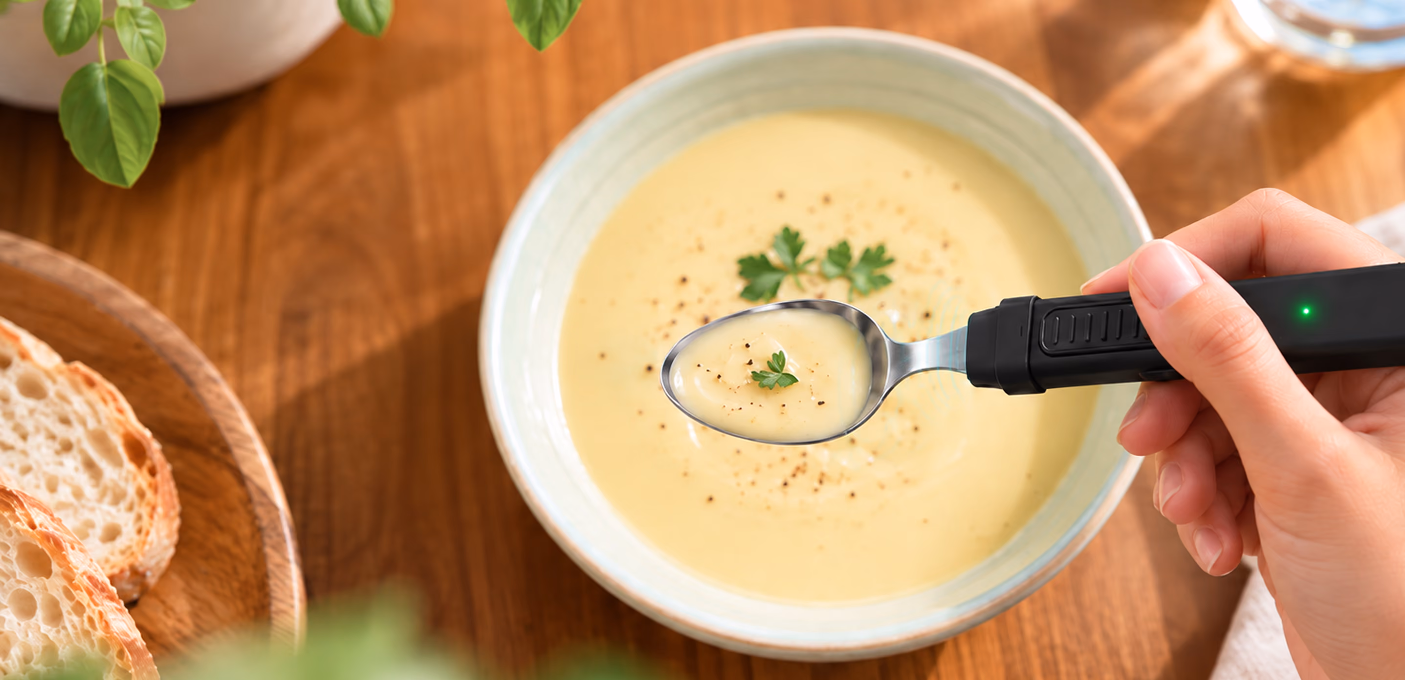 Hand lifting a spoonful of soup with the BiteQ smart spoon