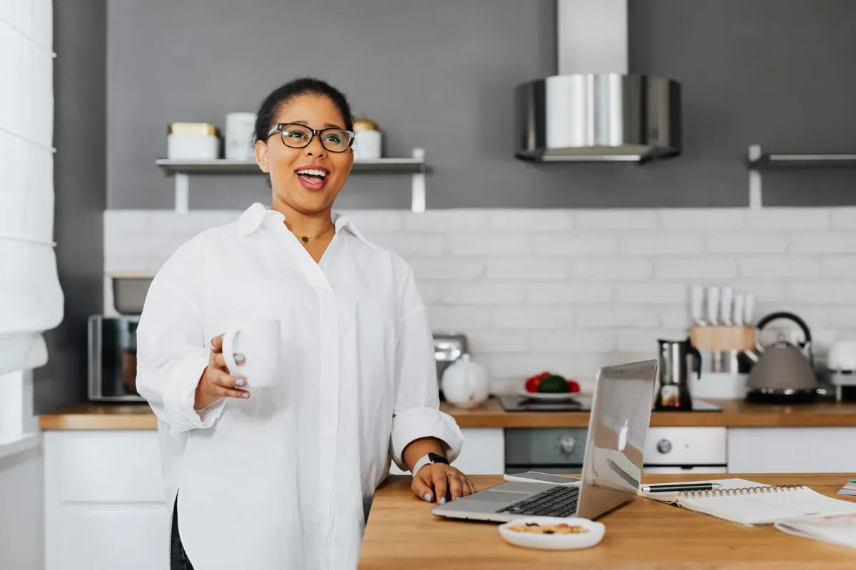 Woman laughing with a mug in her kitchen