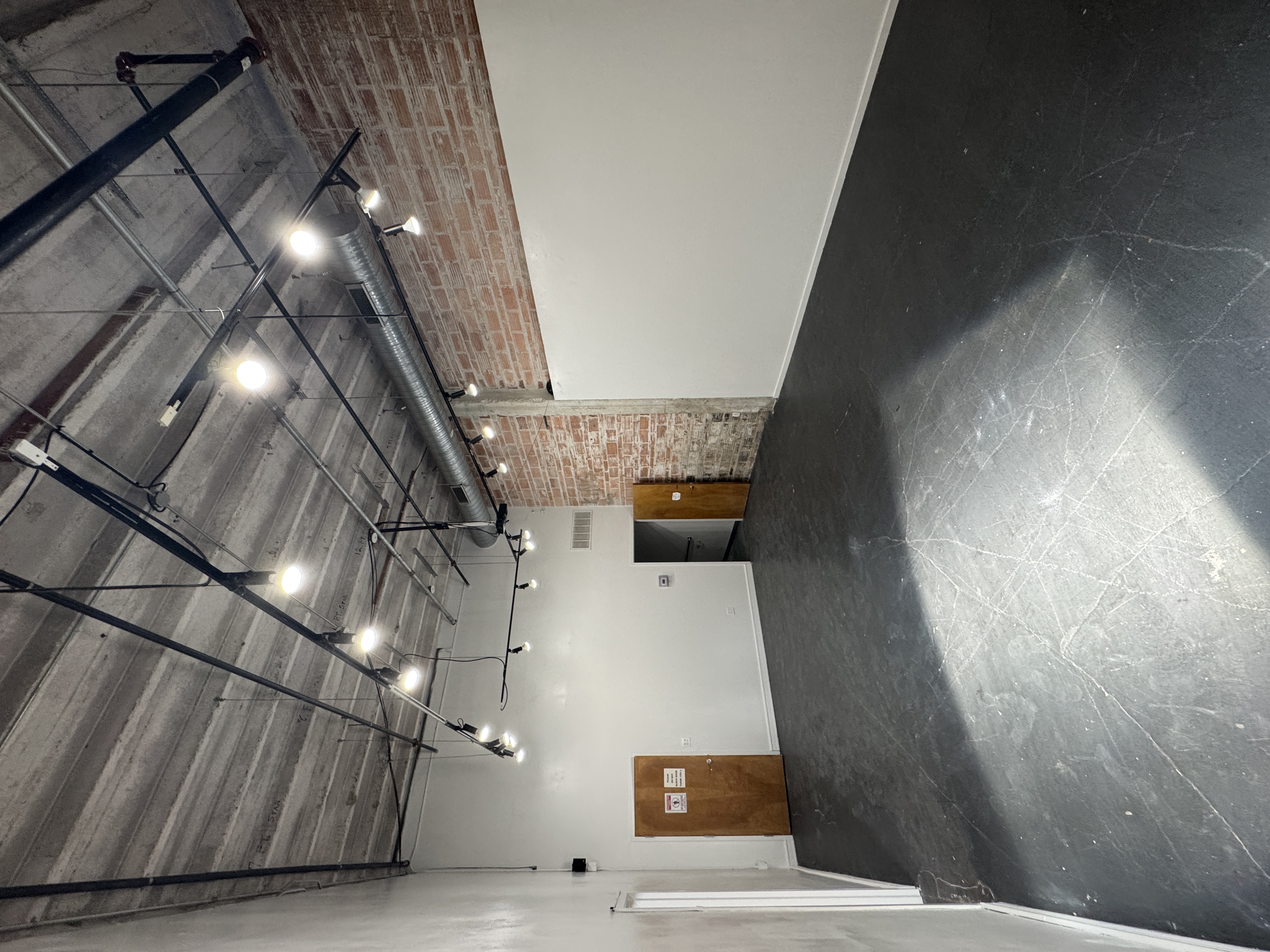 The empty main hall at 108 Blue Star, with track lighting, brick and white walls